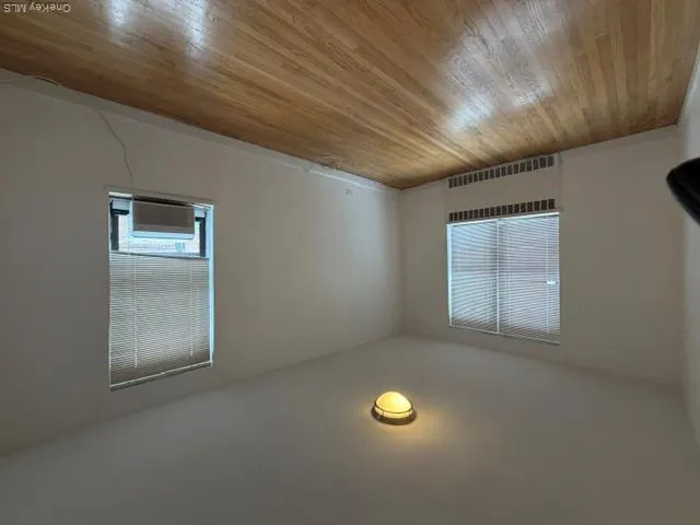 Hardwood flooring, painted walls, window with blinds, ceiling-mounted light fixture, and window-mounted air conditioning unit Hardwood flooring, painted walls, window with blinds, ceiling-mounted light fixture, and window-mounted air conditioning unit