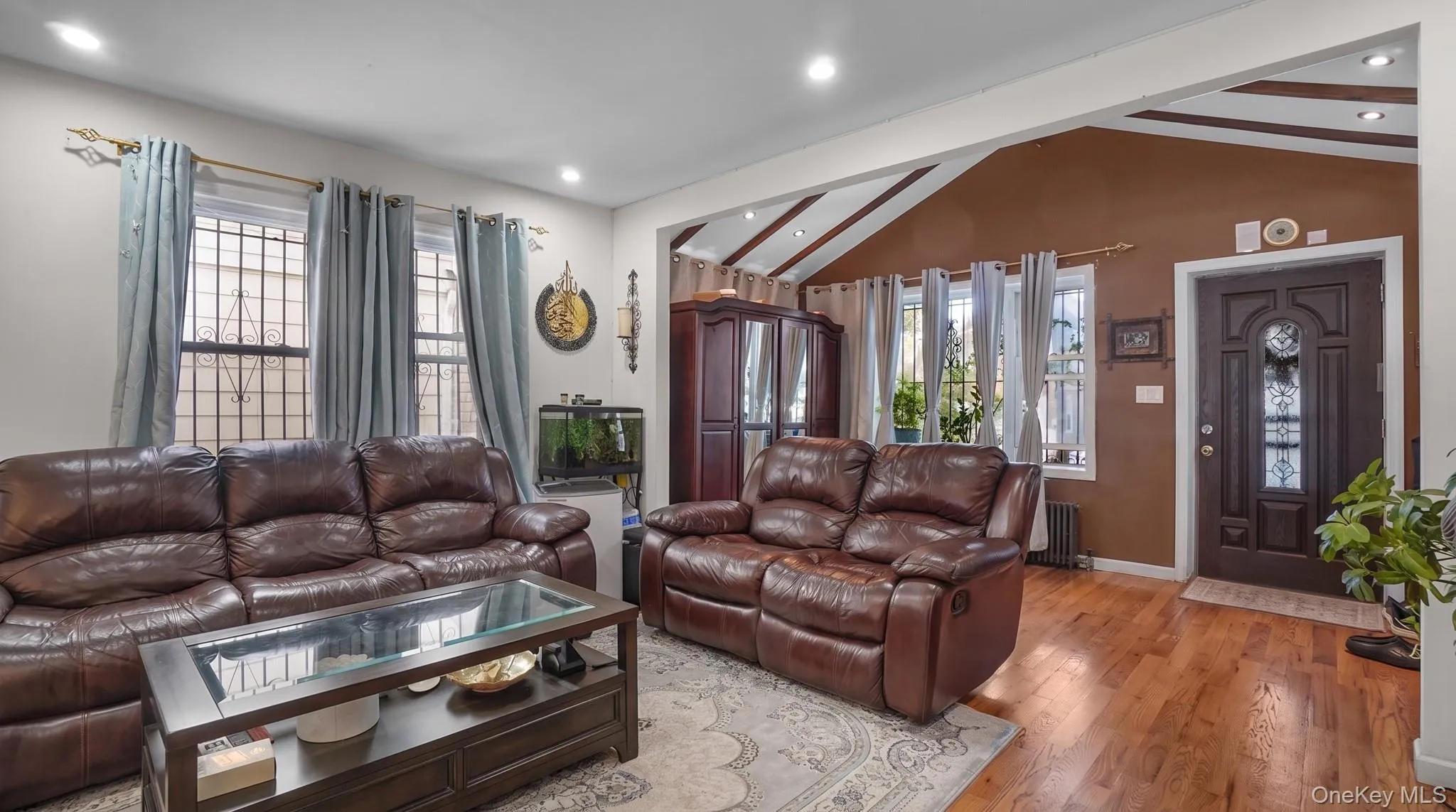 Hardwood flooring, recessed lighting, vaulted ceiling with exposed beams, decorative front entry door with leaded glass, and window security bars Hardwood flooring, recessed lighting, vaulted ceiling with exposed beams, decorative front entry door with leaded glass, and window security bars