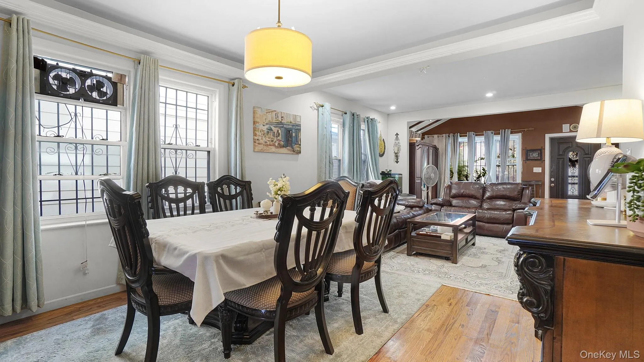 Dining area with wood-finish flooring, two large windows, and a drum pendant light fixture Dining area with wood-finish flooring, two large windows, and a drum pendant light fixture