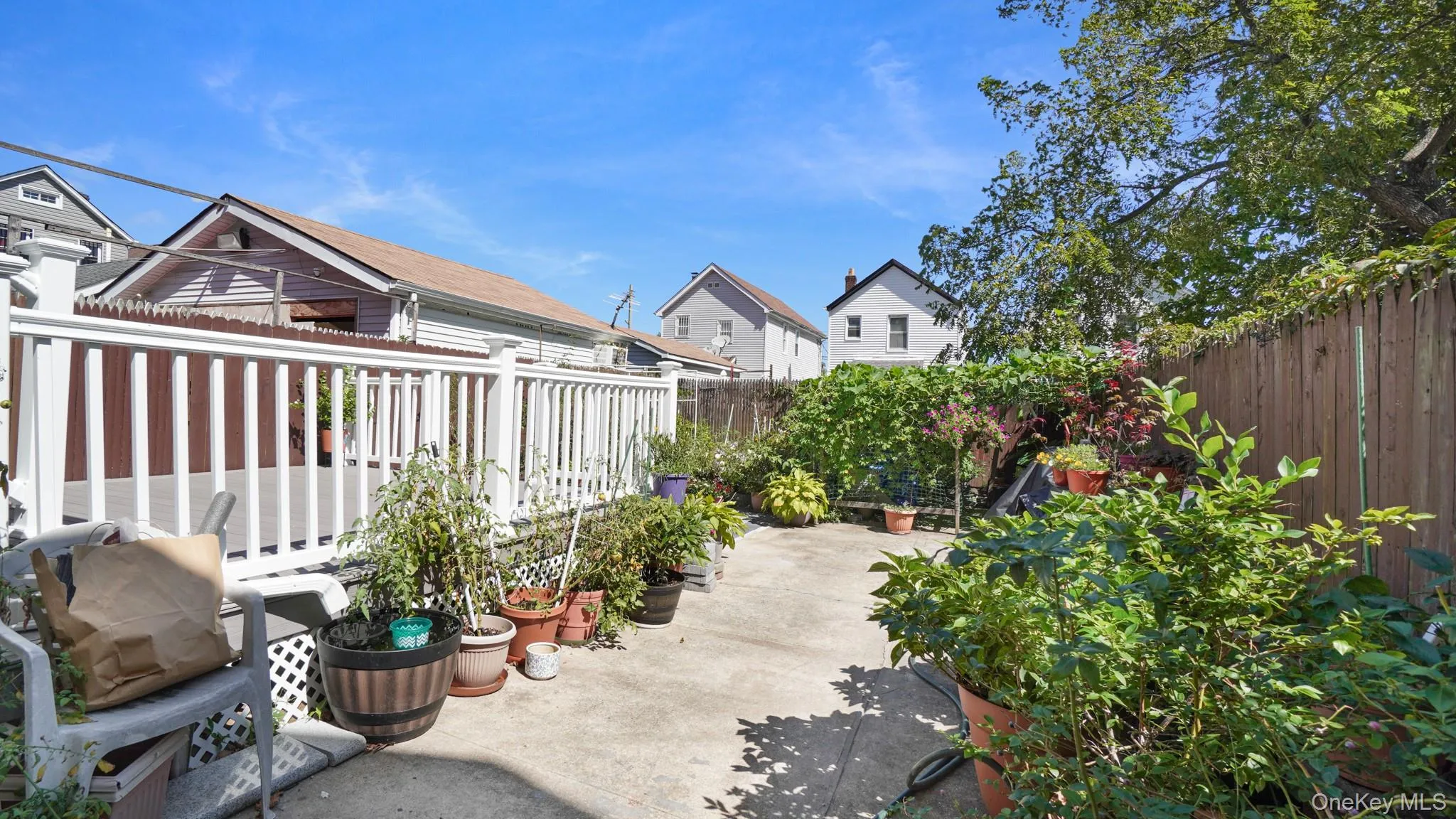 Outdoor patio space with a white-railed deck and perimeter fencing Outdoor patio space with a white-railed deck and perimeter fencing