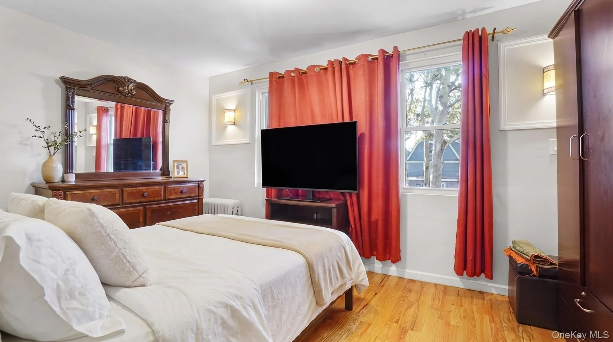 Hardwood flooring, wall-mounted lighting fixtures, and natural light from a double-hung window Hardwood flooring, wall-mounted lighting fixtures, and natural light from a double-hung window