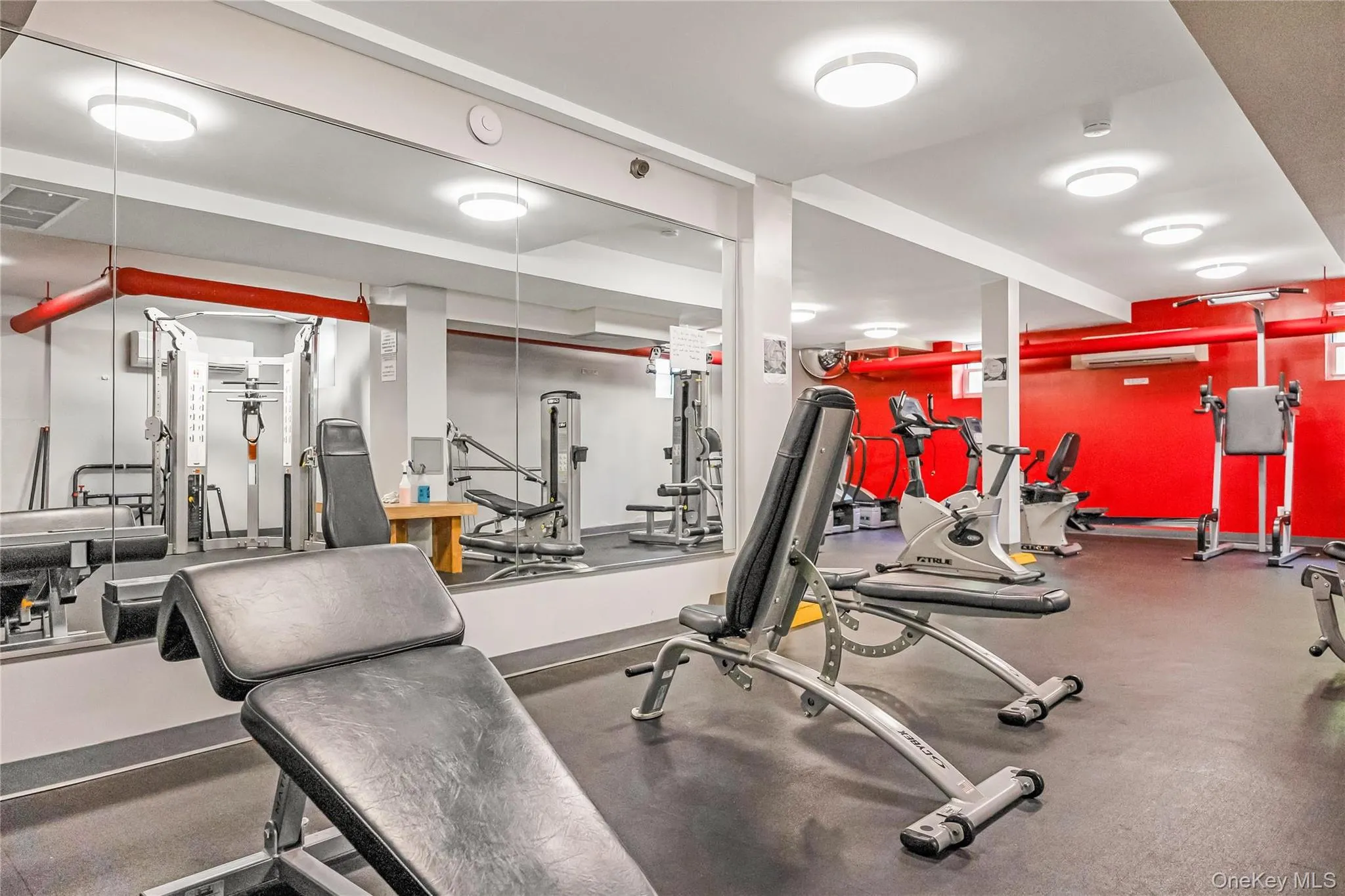 Dedicated fitness area with rubberized flooring, mirrored walls, and recessed lighting Dedicated fitness area with rubberized flooring, mirrored walls, and recessed lighting