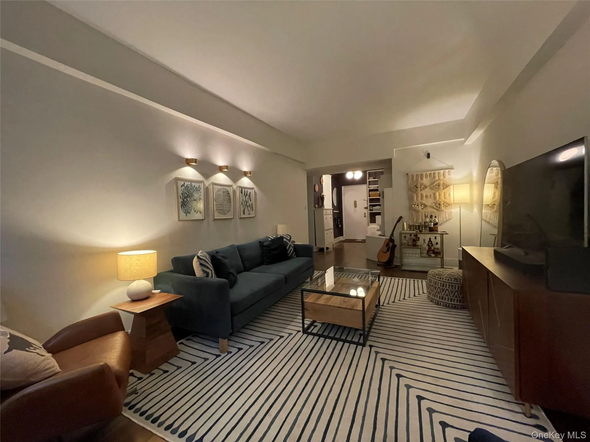 Recessed ceiling, three wall-mounted sconces, light-toned walls, wood-finish flooring, and a built-in media console Recessed ceiling, three wall-mounted sconces, light-toned walls, wood-finish flooring, and a built-in media console