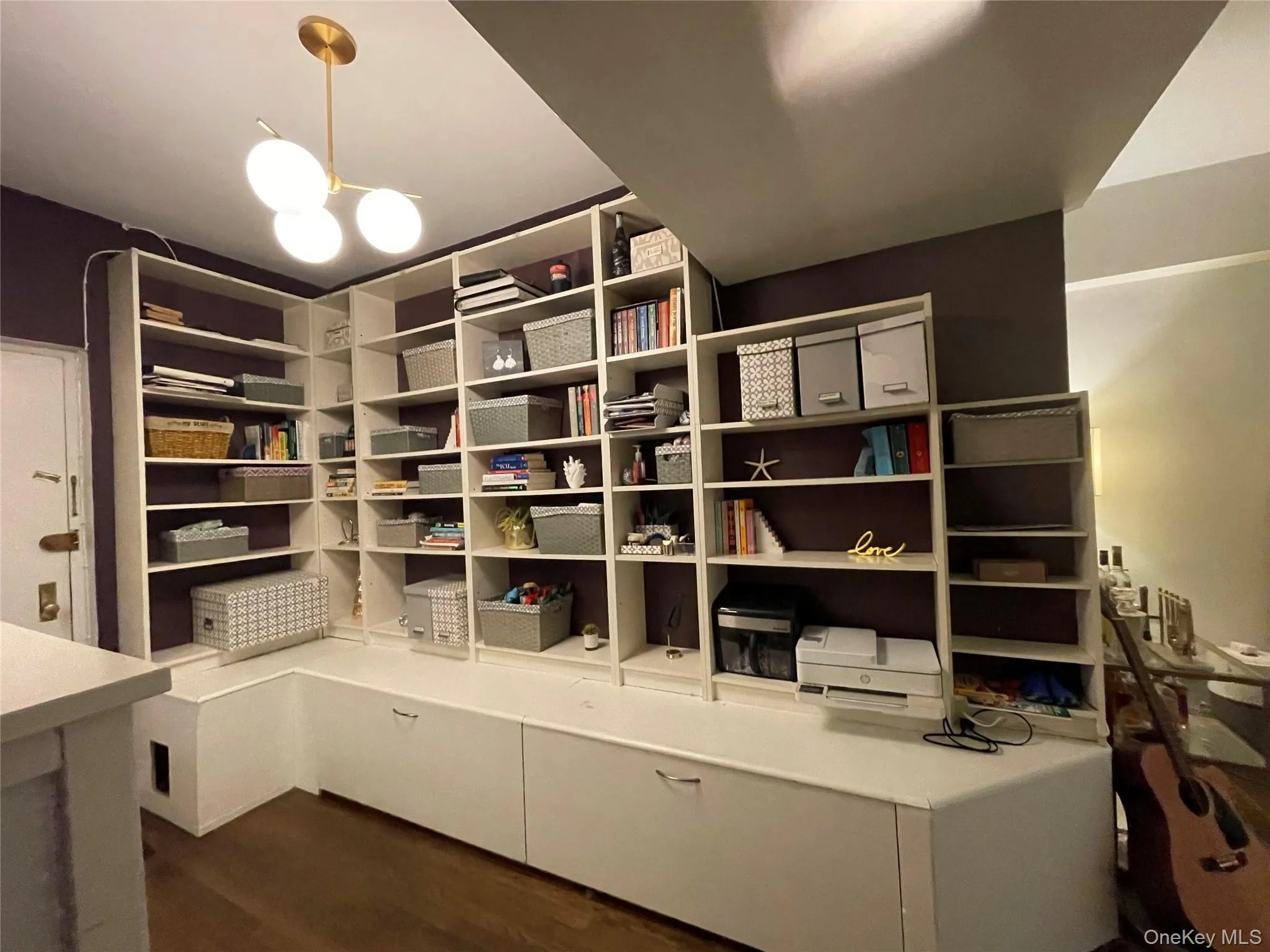 Extensive built-in white shelving, integrated white cabinetry, and wood-finish flooring Extensive built-in white shelving, integrated white cabinetry, and wood-finish flooring