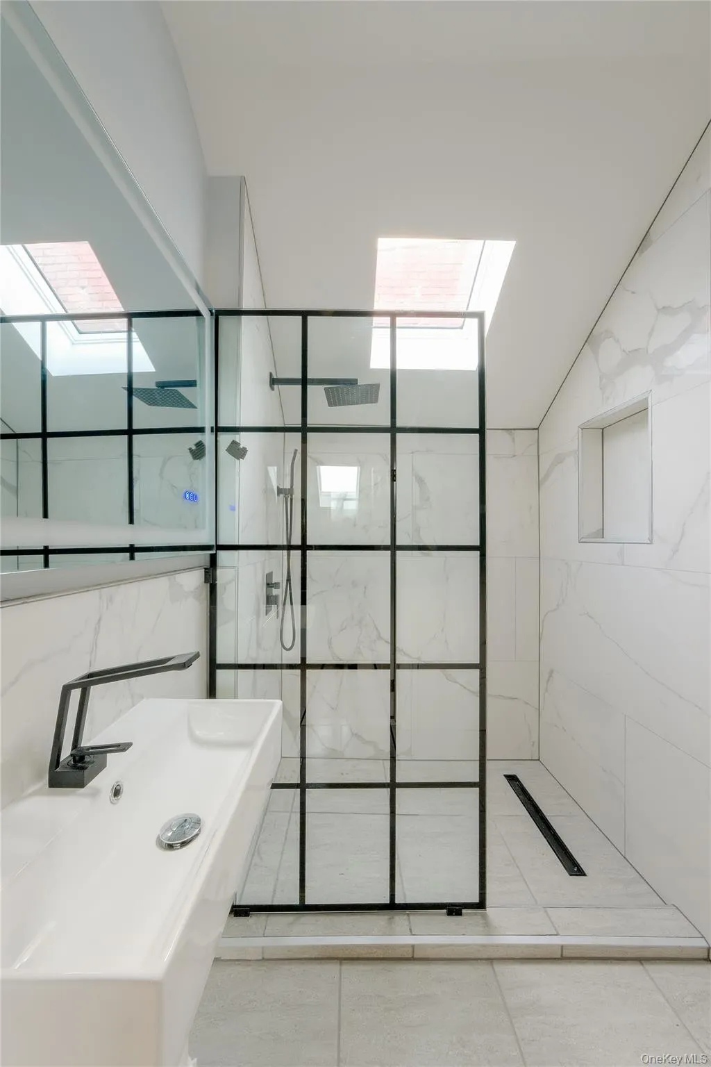 Modern bathroom with a walk-in shower featuring a grid-patterned glass enclosure, dual shower heads, and an integrated linear drain Modern bathroom with a walk-in shower featuring a grid-patterned glass enclosure, dual shower heads, and an integrated linear drain