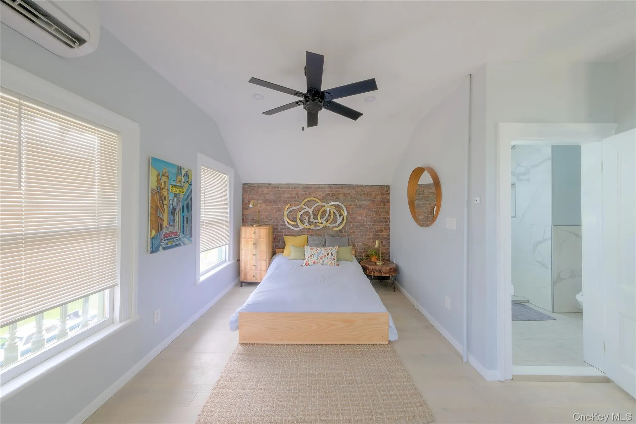 Vaulted ceiling with a black ceiling fan, brick accent wall, white-framed windows, and light-tone flooring Vaulted ceiling with a black ceiling fan, brick accent wall, white-framed windows, and light-tone flooring