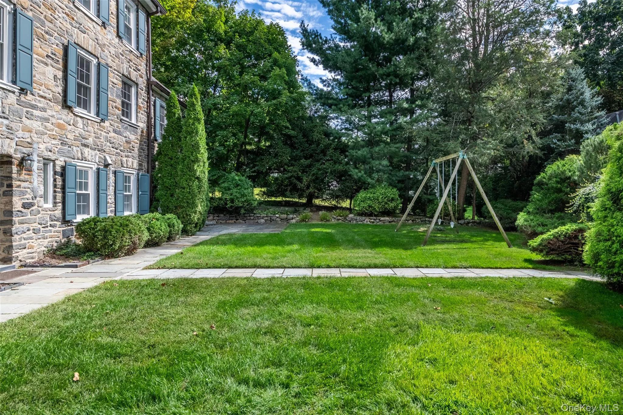 Stone exterior with shuttered windows, a manicured lawn, and mature trees Stone exterior with shuttered windows, a manicured lawn, and mature trees