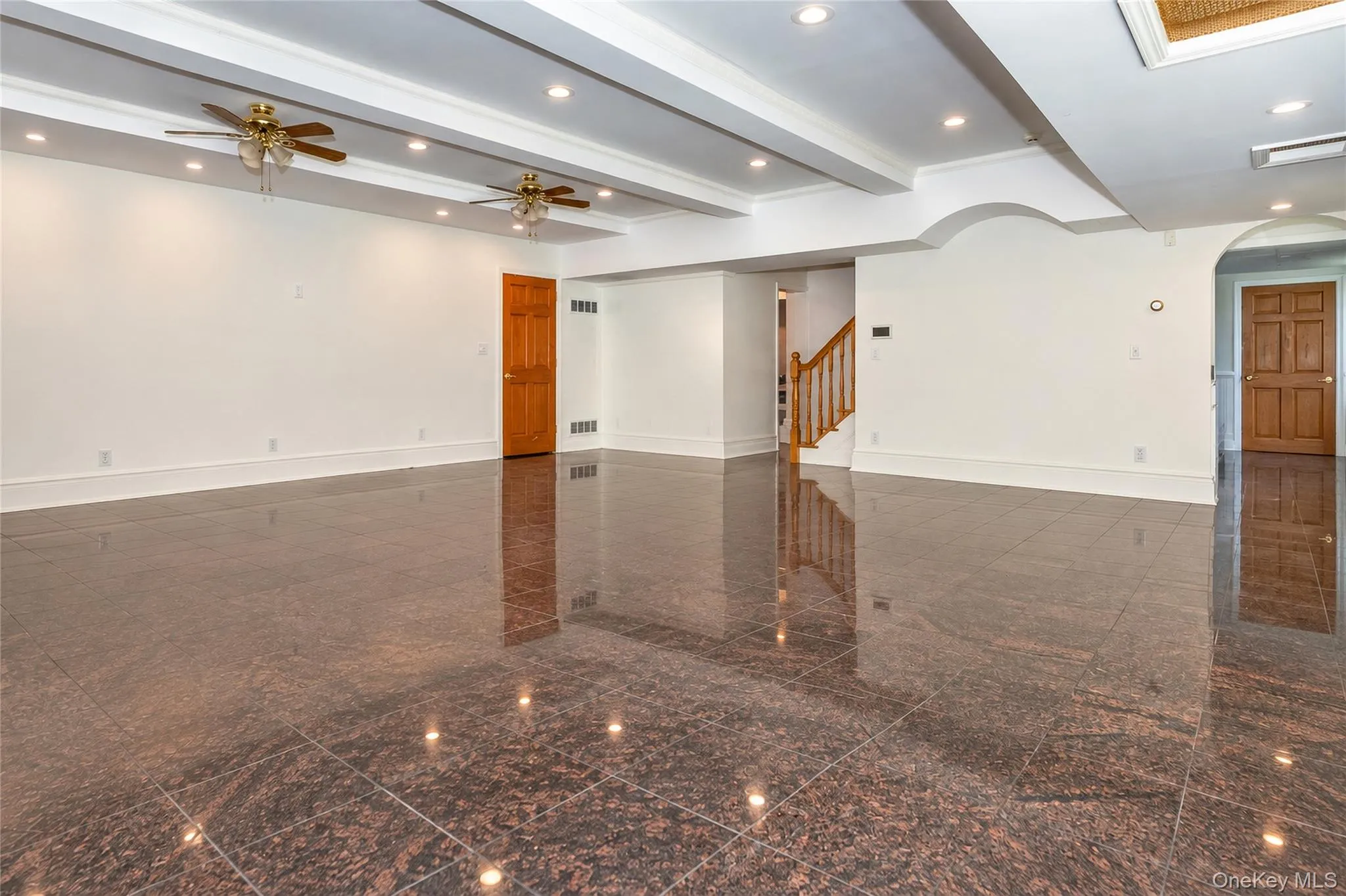 Spacious room featuring polished stone flooring, recessed lighting, ceiling fans, and a tray ceiling with crown molding Spacious room featuring polished stone flooring, recessed lighting, ceiling fans, and a tray ceiling with crown molding
