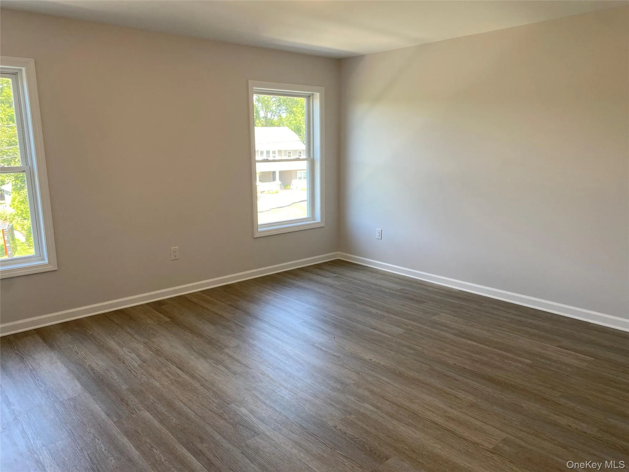 Unfurnished room with dark wood-style flooring and baseboards Unfurnished room with dark wood-style flooring and baseboards