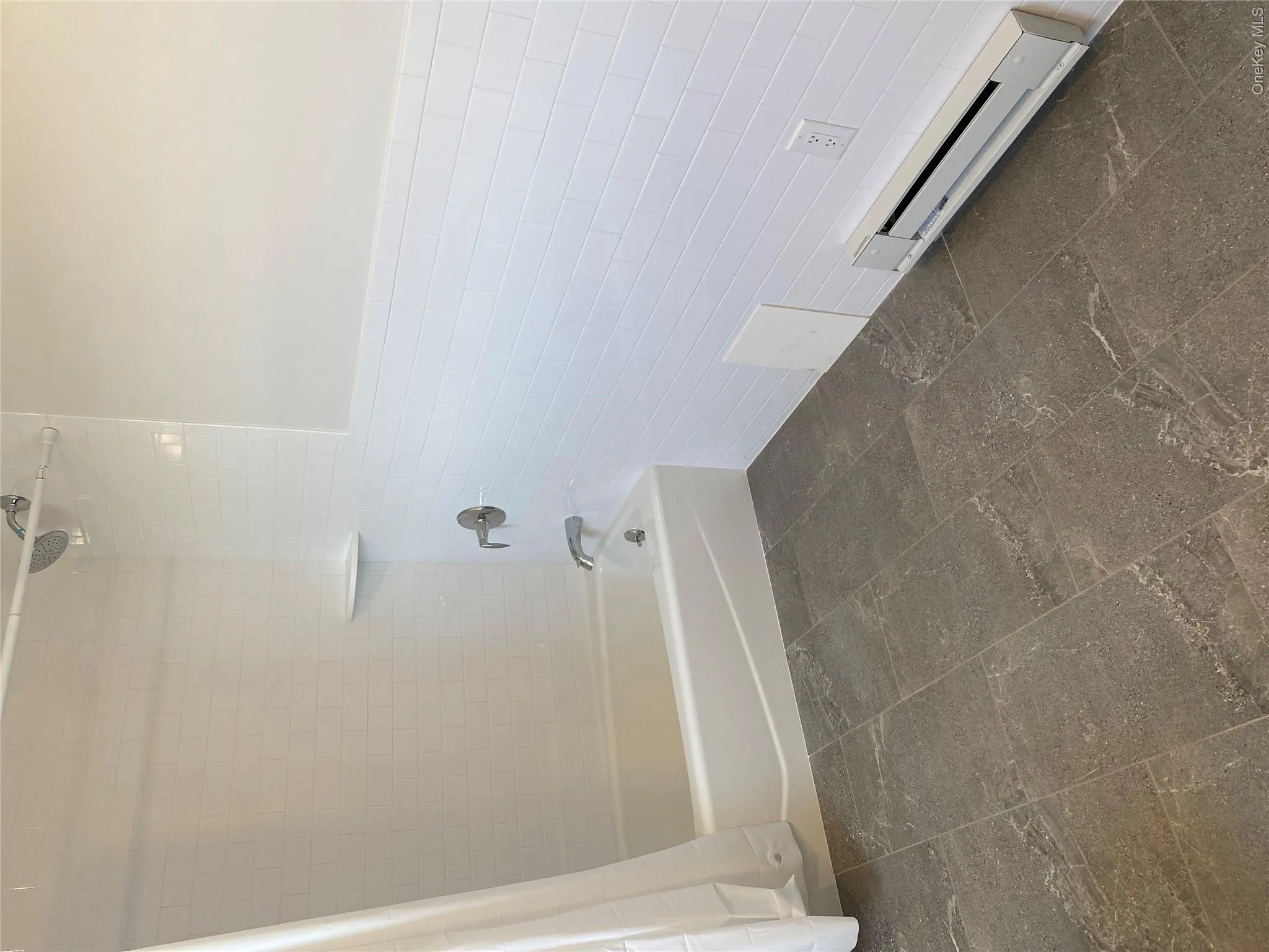 Full bathroom featuring tile walls, shower / bathtub combination with curtain, a baseboard heating unit, and a wainscoted wall Full bathroom featuring tile walls, shower / bathtub combination with curtain, a baseboard heating unit, and a wainscoted wall