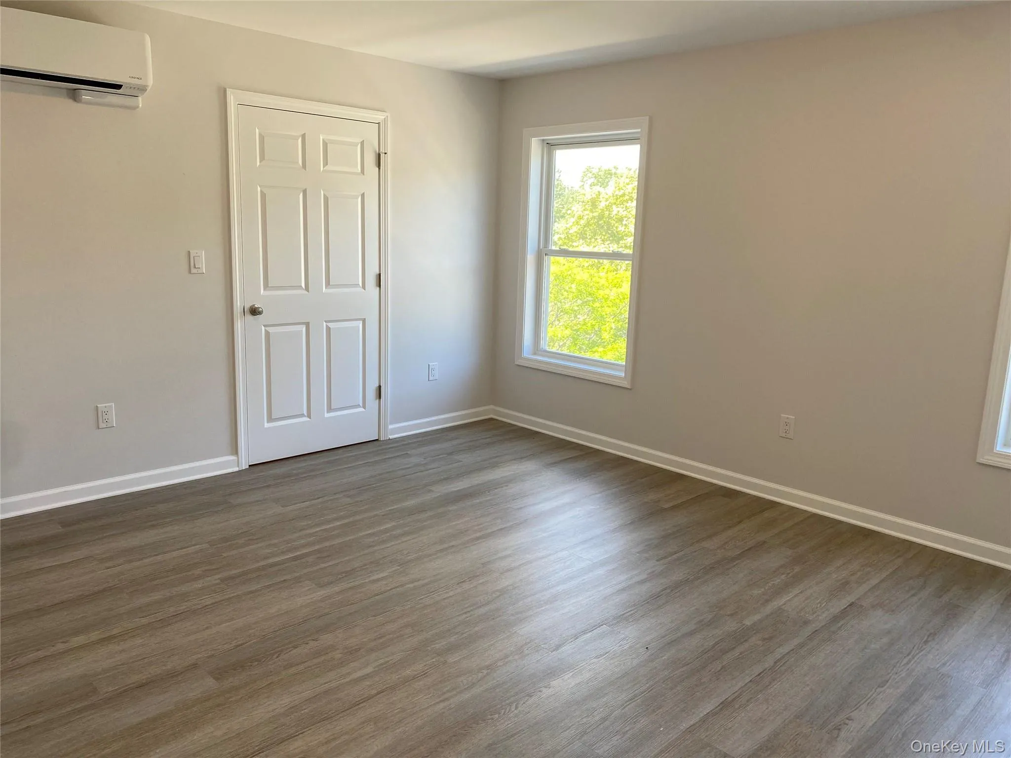 Spare room with dark wood-type flooring and a wall mounted air conditioner Spare room with dark wood-type flooring and a wall mounted air conditioner