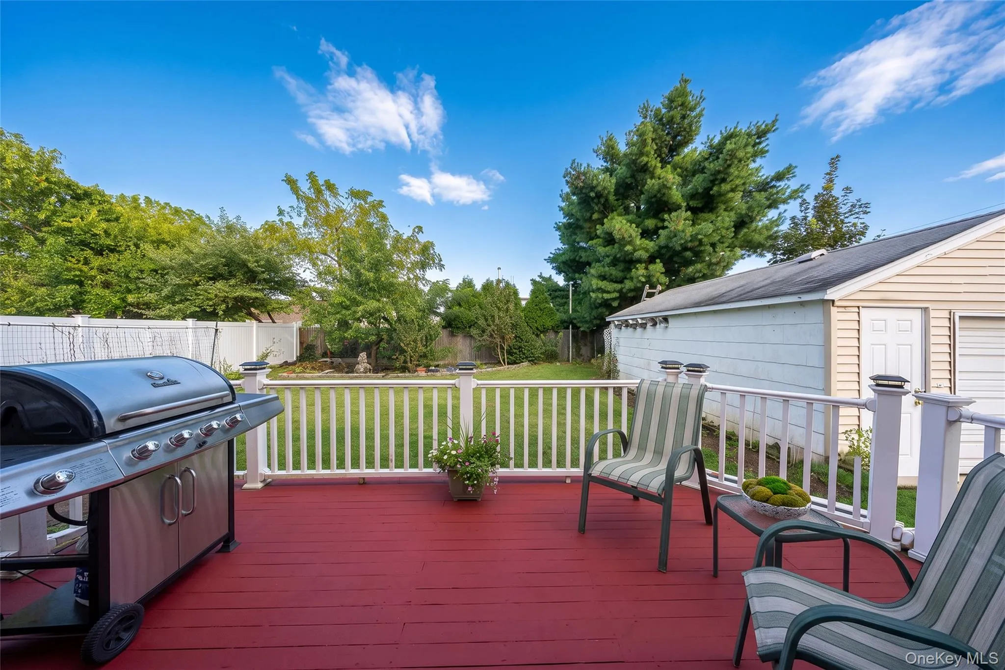 Expansive red-stained deck with white railing, leading to a green lawn Expansive red-stained deck with white railing, leading to a green lawn