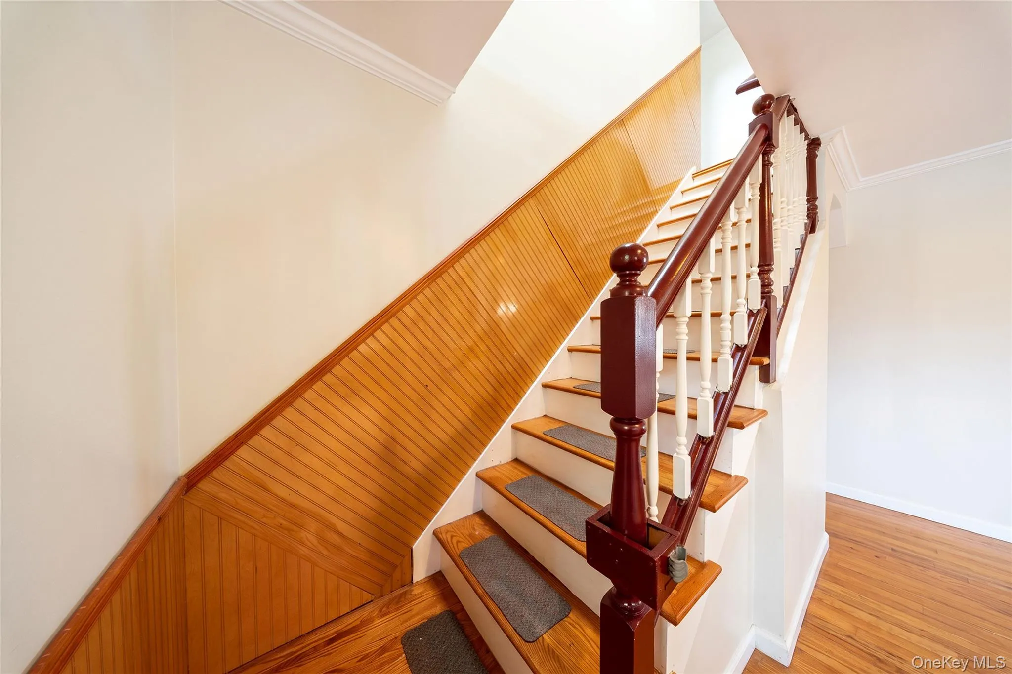 Staircase featuring wood treads, white risers, and a rich wood newel post with balusters Staircase featuring wood treads, white risers, and a rich wood newel post with balusters