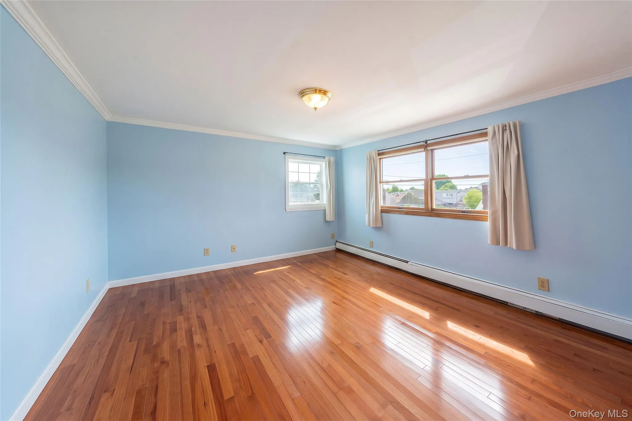 Hardwood flooring throughout, multiple windows, crown molding, and a flush mount light fixture Hardwood flooring throughout, multiple windows, crown molding, and a flush mount light fixture