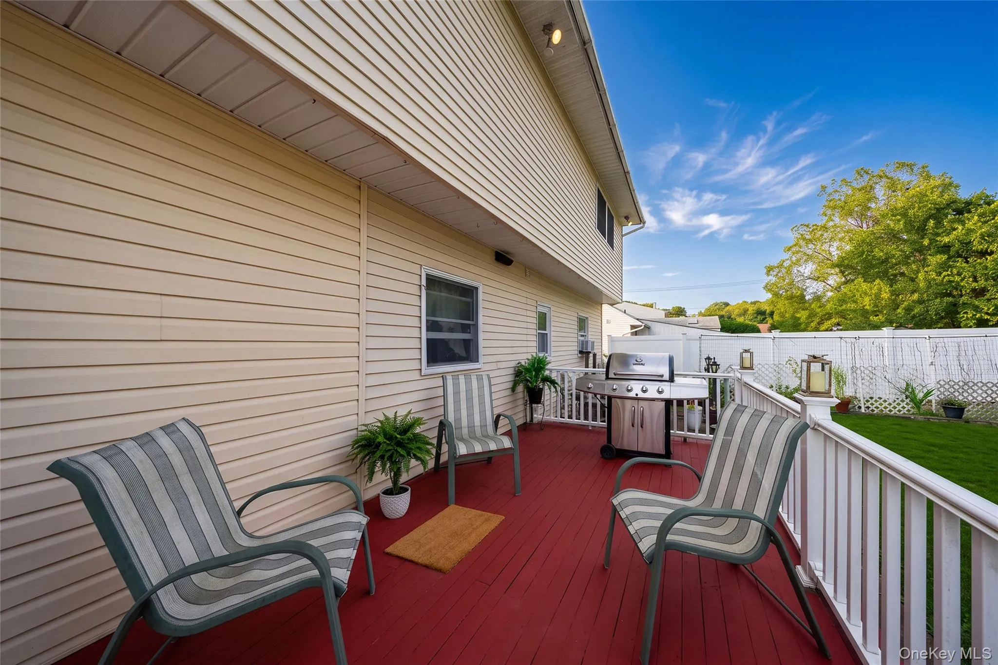 Red-stained wood deck with white railings and vinyl siding Red-stained wood deck with white railings and vinyl siding