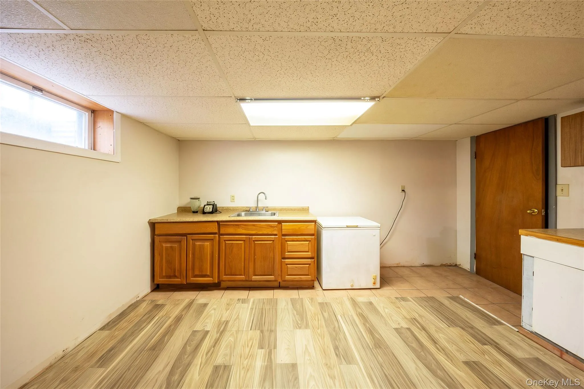 Wood-finish flooring, drop ceiling, built-in cabinetry, stainless steel sink, and a high window Wood-finish flooring, drop ceiling, built-in cabinetry, stainless steel sink, and a high window