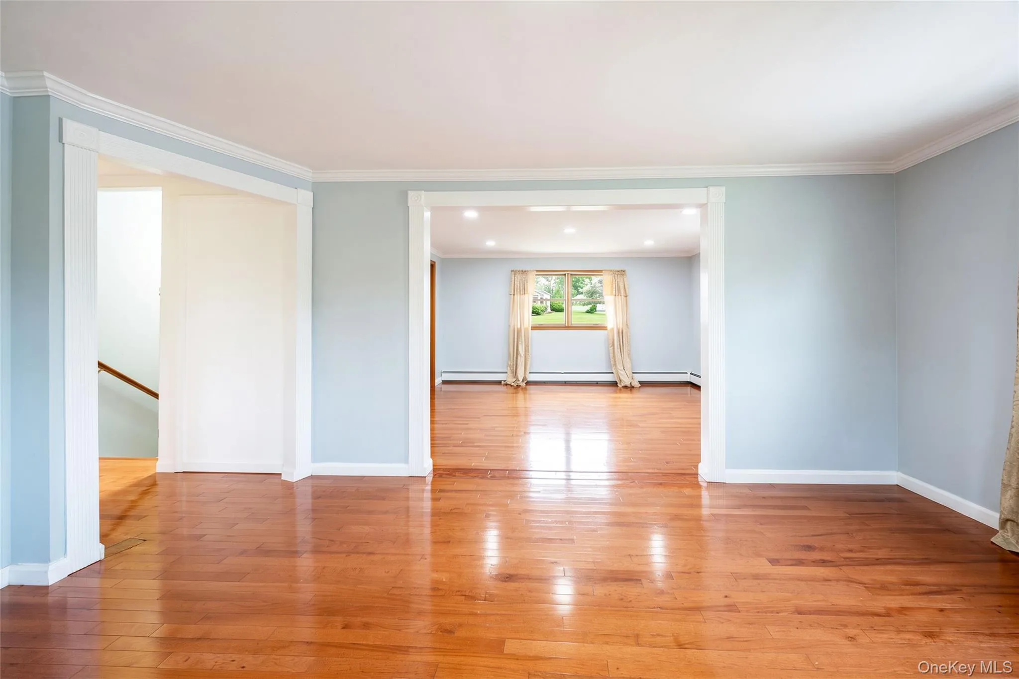 Polished wood-finish flooring, white trim details, recessed lighting, and a prominent window framing outdoor greenery Polished wood-finish flooring, white trim details, recessed lighting, and a prominent window framing outdoor greenery