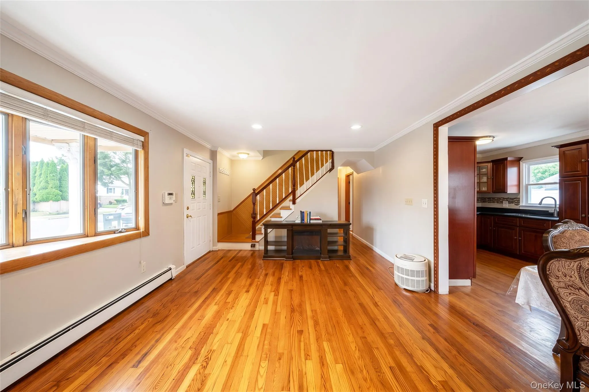 Hardwood flooring, white crown molding, recessed lighting, white entry door with decorative glass, and a finished staircase with wood handrails Hardwood flooring, white crown molding, recessed lighting, white entry door with decorative glass, and a finished staircase with wood handrails