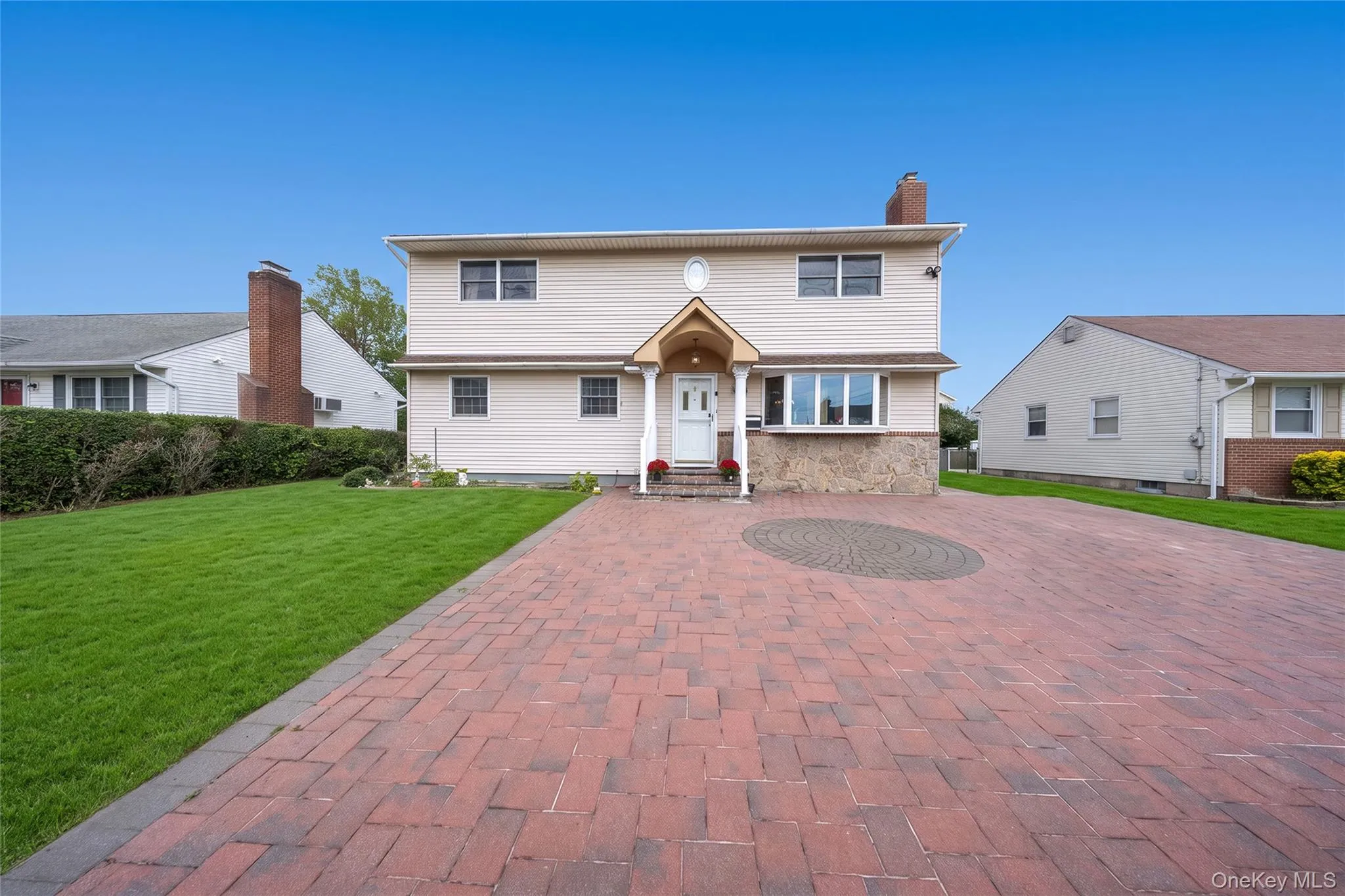 Brick paver driveway with a circular inlay, leading to a covered entryway Brick paver driveway with a circular inlay, leading to a covered entryway