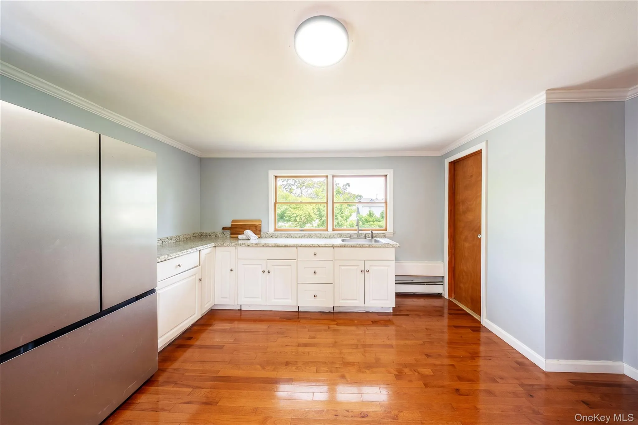 Hardwood flooring, white cabinetry, integrated sink, and stainless steel refrigerator Hardwood flooring, white cabinetry, integrated sink, and stainless steel refrigerator