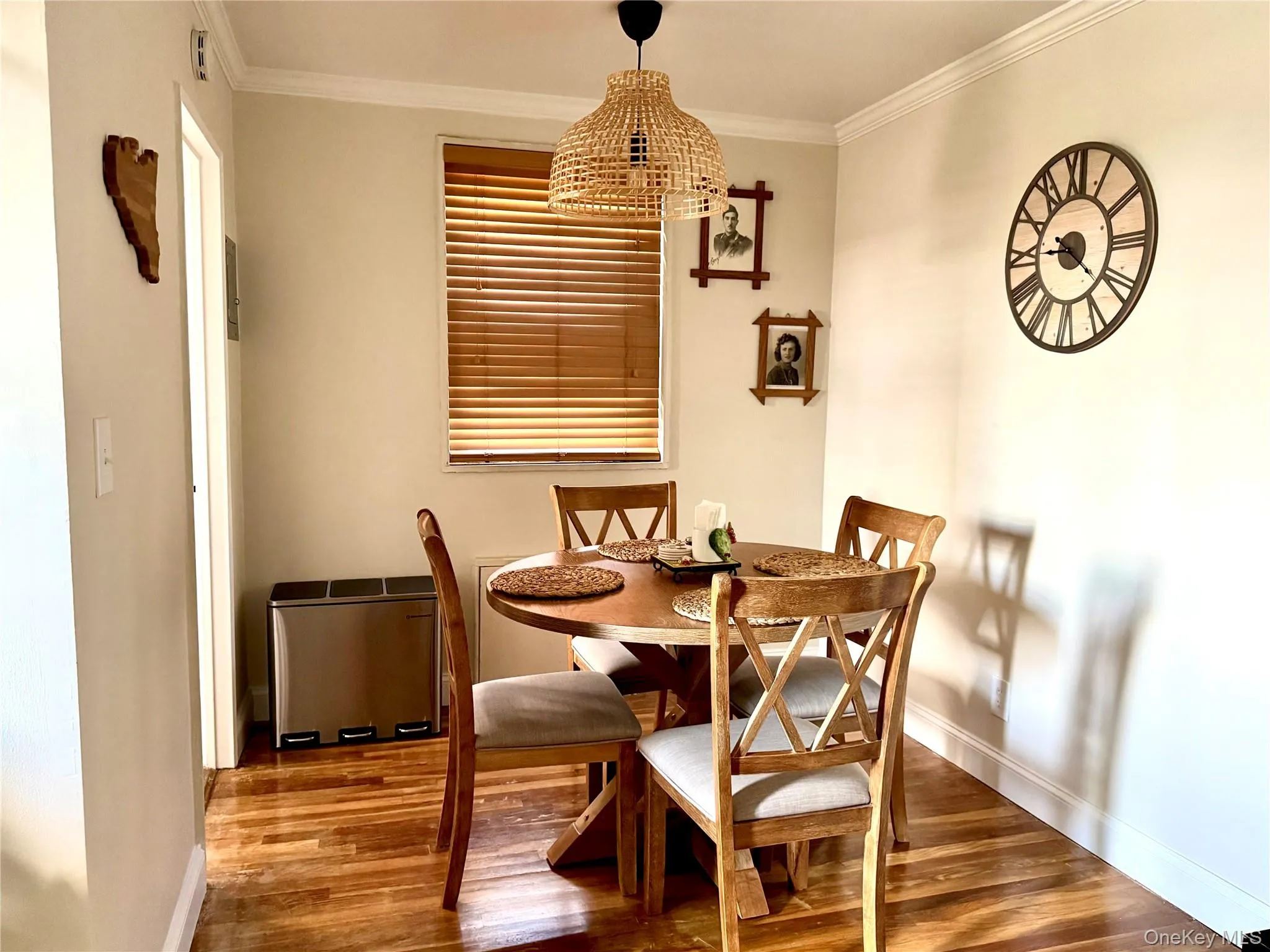 Wood-finish flooring, crown molding, and a window with wood blinds Wood-finish flooring, crown molding, and a window with wood blinds