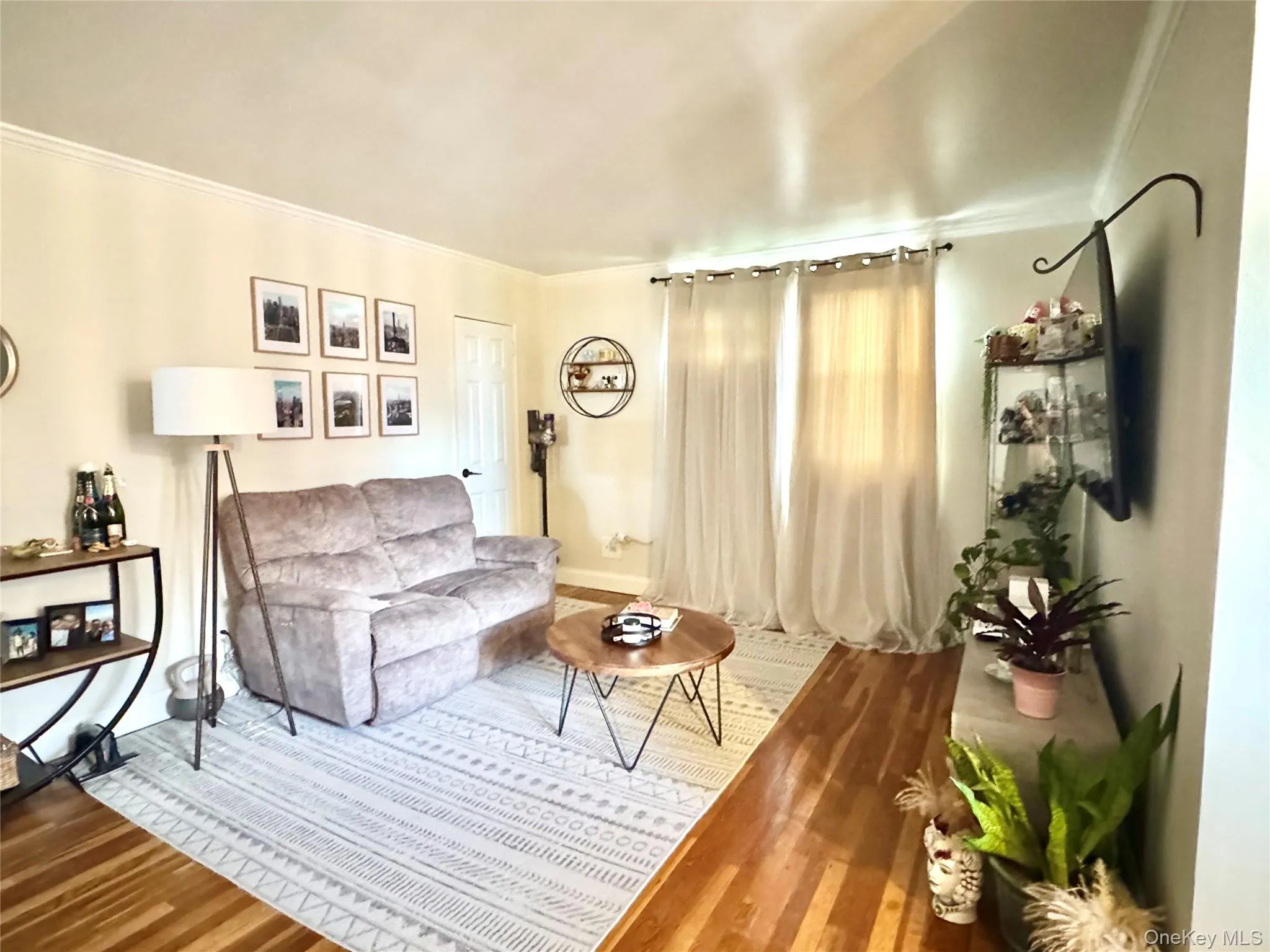 Wood-finish flooring, crown molding, and a closet door with black hardware Wood-finish flooring, crown molding, and a closet door with black hardware