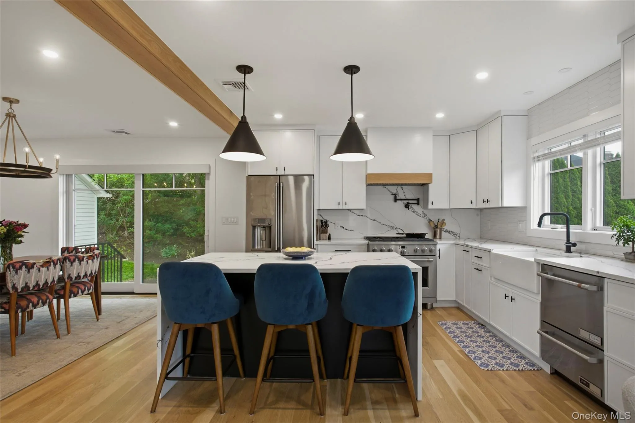 Open kitchen with waterfall island, counter seating, and stainless steel appliances. Open kitchen with waterfall island, counter seating, and stainless steel appliances.