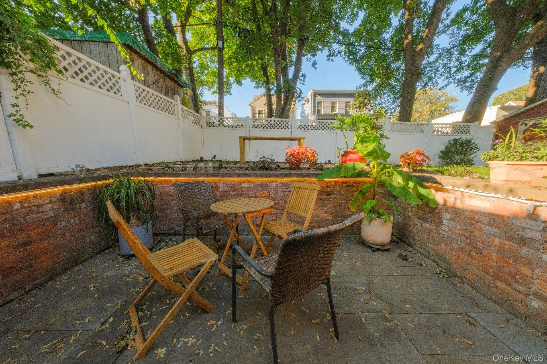 Sunken brick patio with stone slab flooring, surrounded by a lattice-topped privacy fence and mature trees Sunken brick patio with stone slab flooring, surrounded by a lattice-topped privacy fence and mature trees