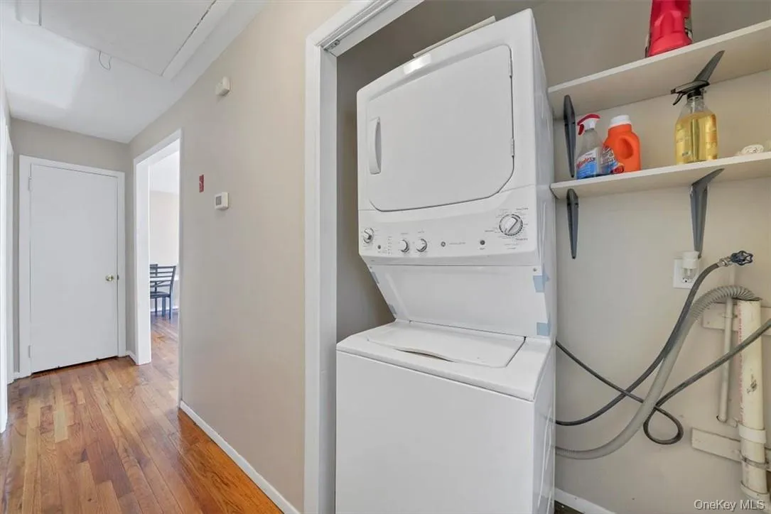 Laundry area with stacked washing maching and dryer and hardwood / wood-style floors Laundry area with stacked washing maching and dryer and hardwood / wood-style floors