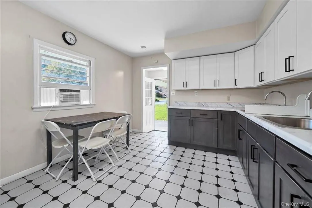 Kitchen featuring gray cabinetry, sink, and white cabinets Kitchen featuring gray cabinetry, sink, and white cabinets