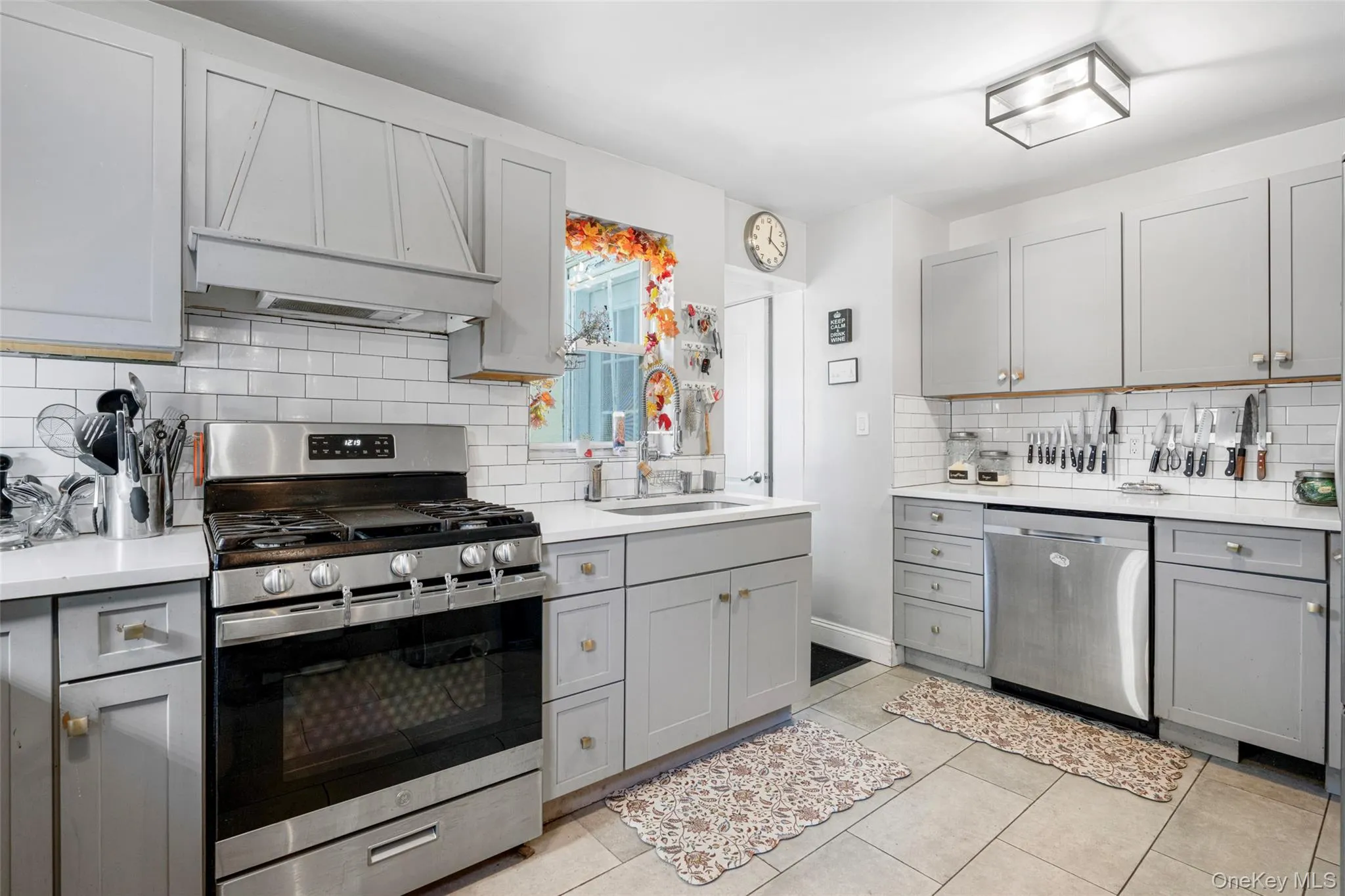 Kitchen featuring stainless steel appliances, premium range hood, sink, and gray cabinetry Kitchen featuring stainless steel appliances, premium range hood, sink, and gray cabinetry