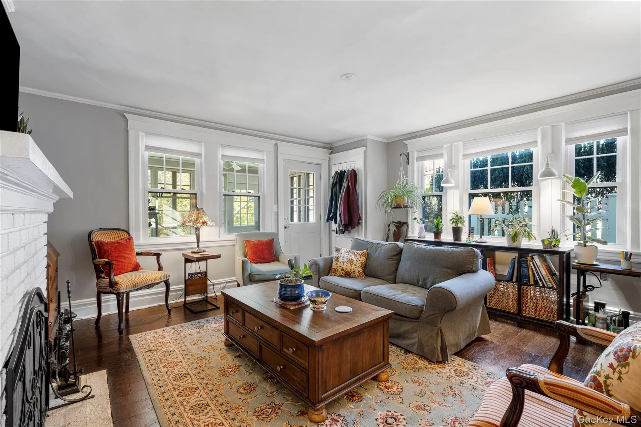 Living room with a fireplace, a wealth of natural light, hardwood / wood-style floors, and crown molding Living room with a fireplace, a wealth of natural light, hardwood / wood-style floors, and crown molding