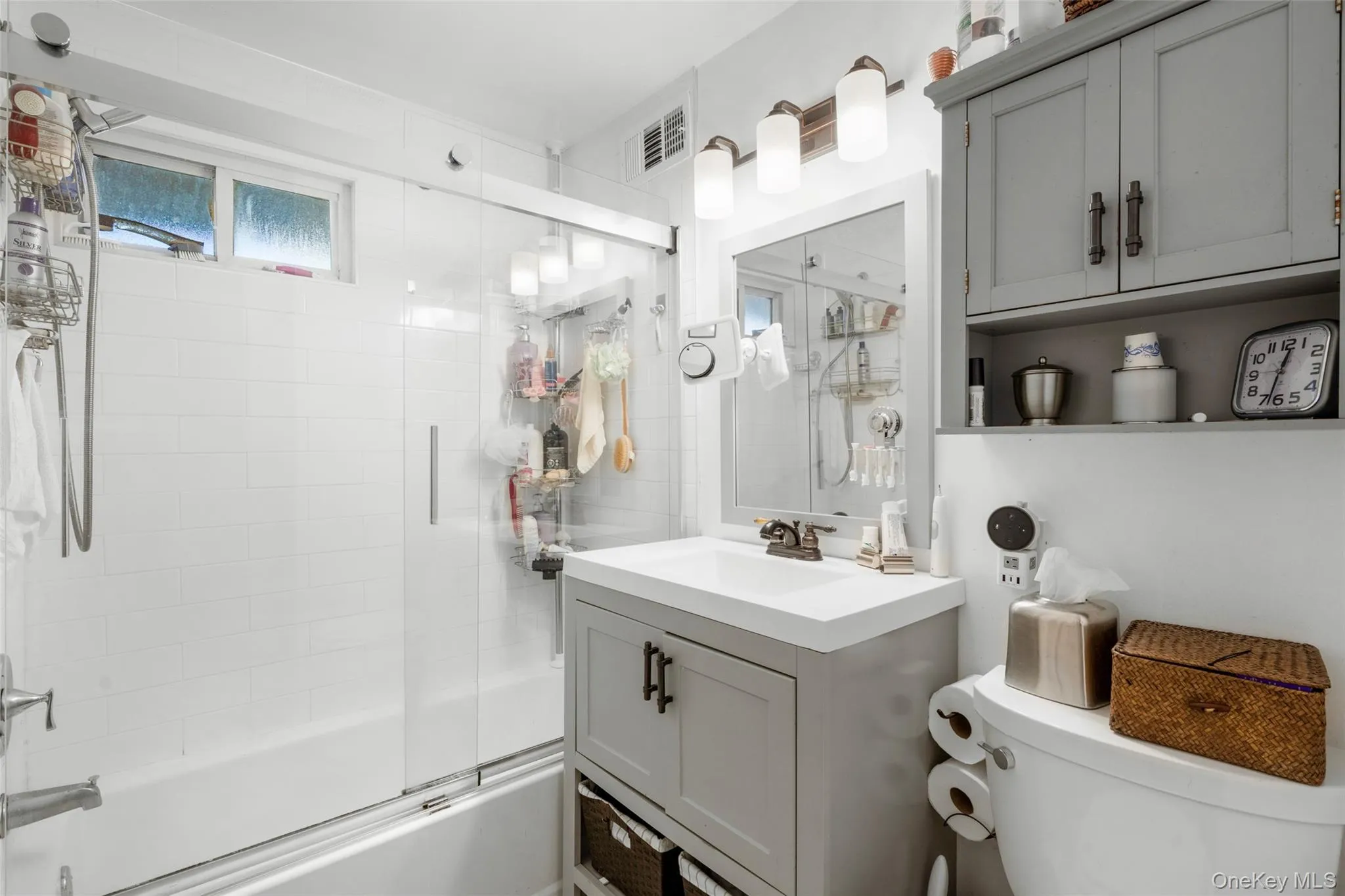 Full bathroom with shower / bath combination with glass door, vanity, and toilet Full bathroom with shower / bath combination with glass door, vanity, and toilet