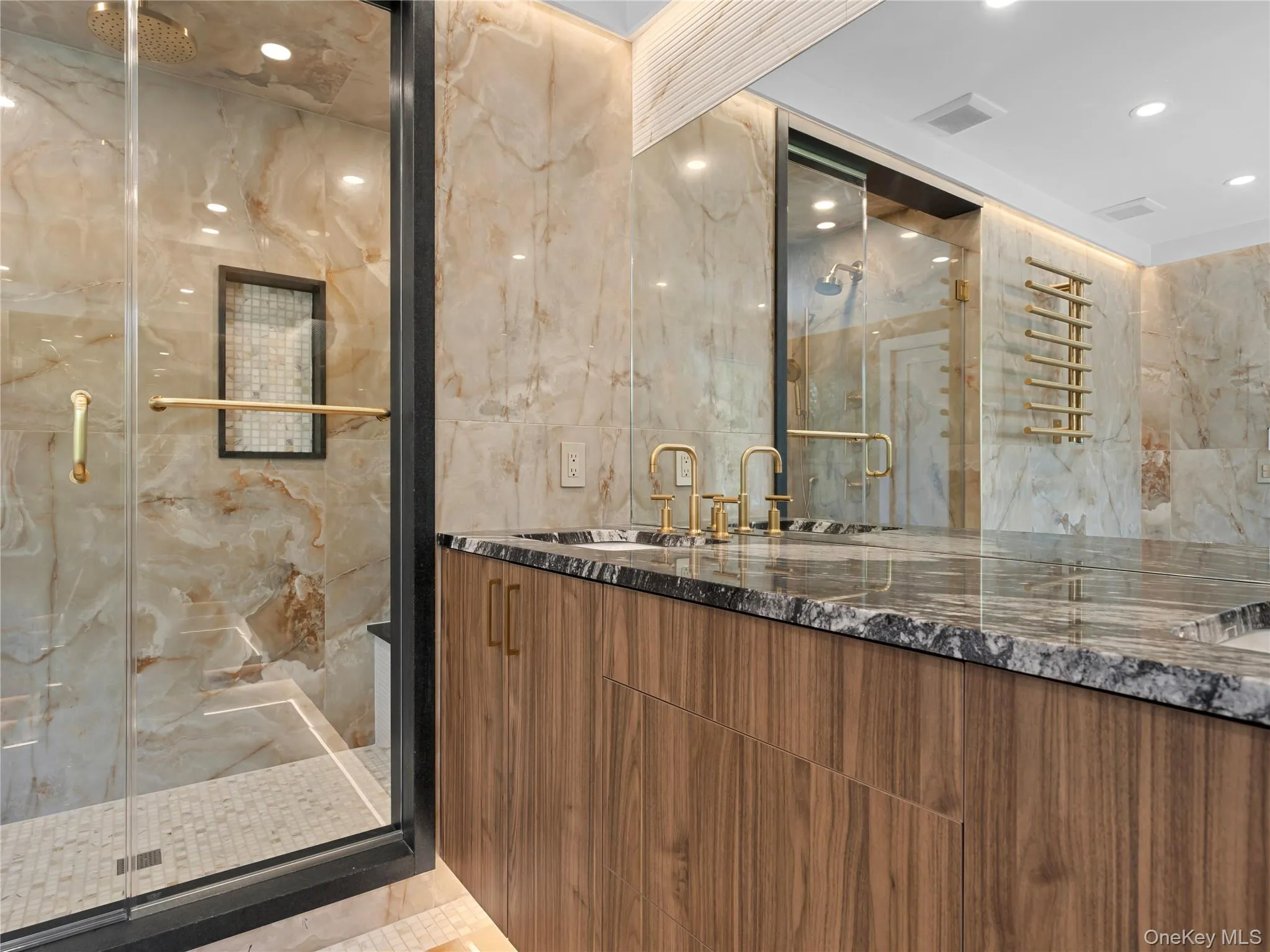 Bathroom with double vanity, a marble finish shower, tile walls, and recessed lighting Bathroom with double vanity, a marble finish shower, tile walls, and recessed lighting