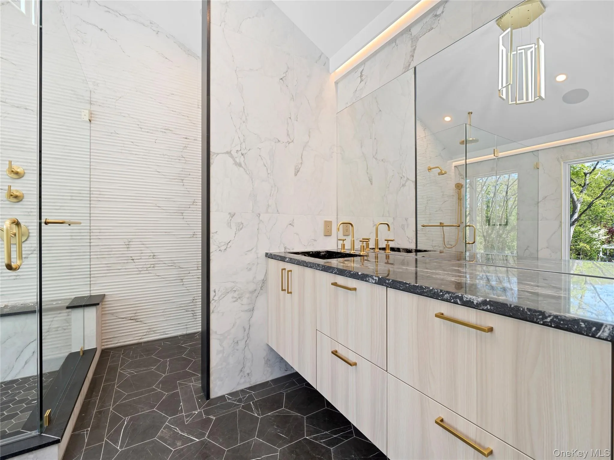 Bathroom featuring tile walls, a marble finish shower, stone wall, vanity, and dark marble finish flooring Bathroom featuring tile walls, a marble finish shower, stone wall, vanity, and dark marble finish flooring