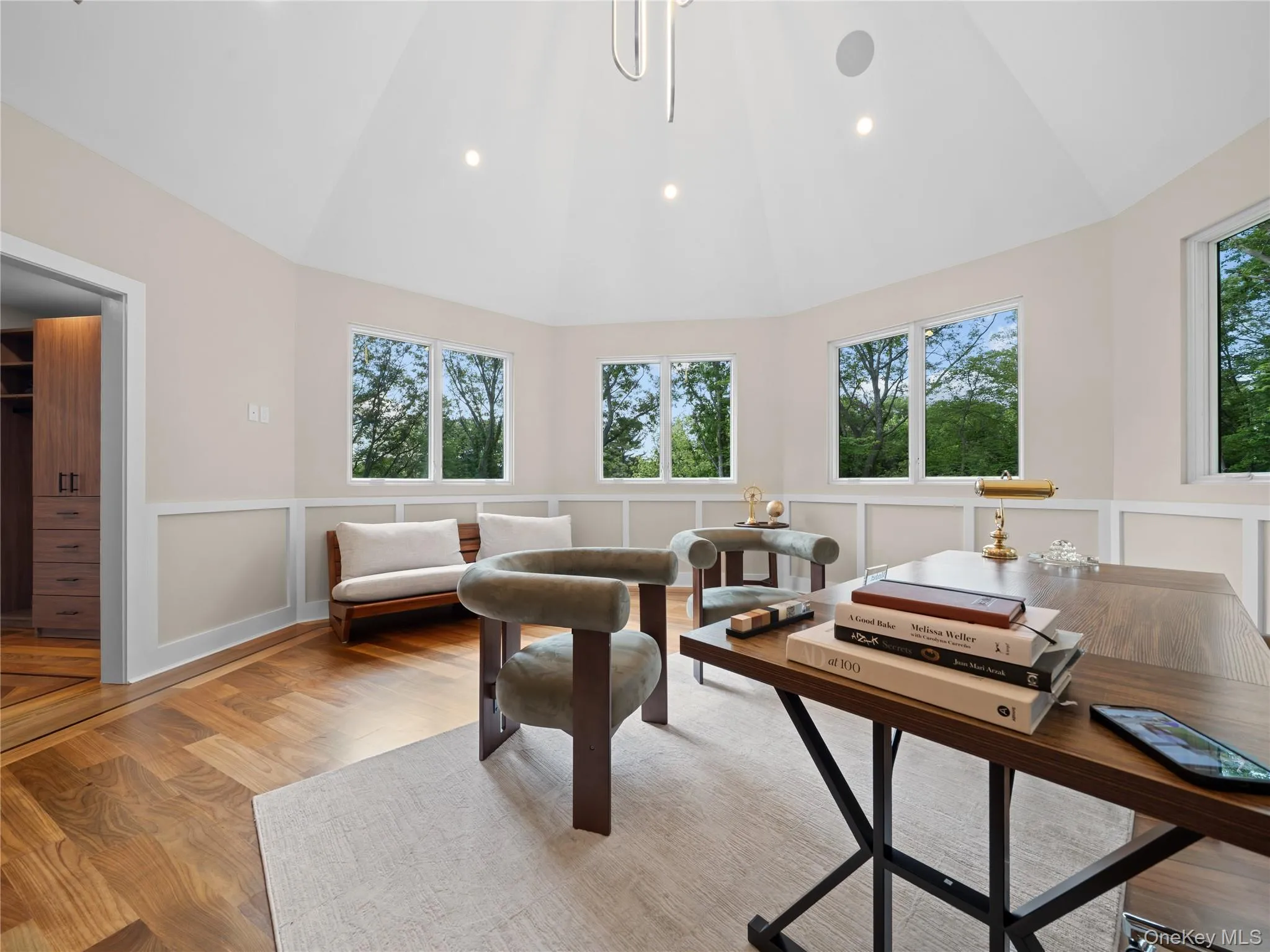 Living room featuring plenty of natural light, a decorative wall, wood finished floors, high vaulted ceiling, and wainscoting Living room featuring plenty of natural light, a decorative wall, wood finished floors, high vaulted ceiling, and wainscoting