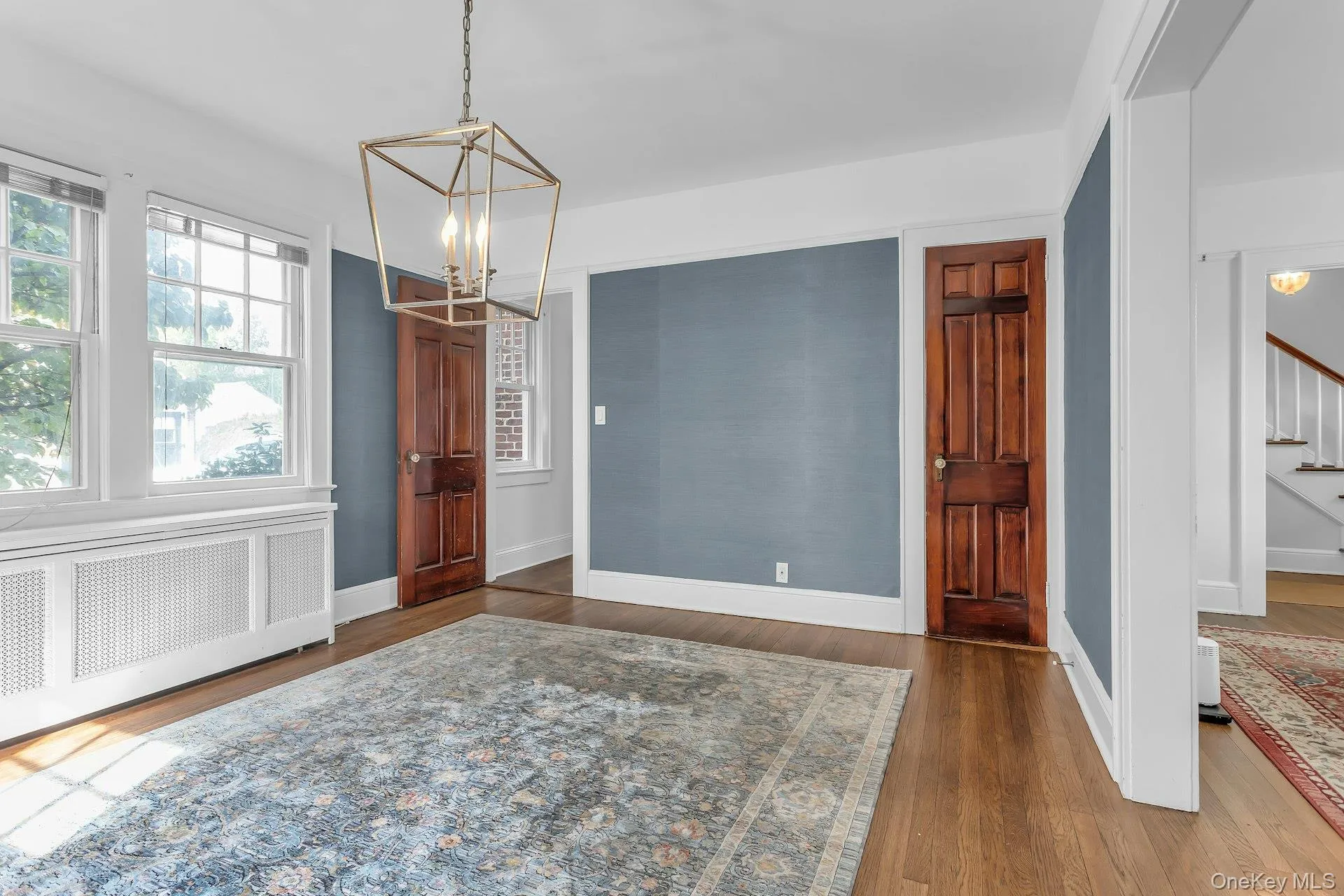 Hardwood flooring, painted walls, white trim, paneled doors, and a decorative ceiling light fixture Hardwood flooring, painted walls, white trim, paneled doors, and a decorative ceiling light fixture