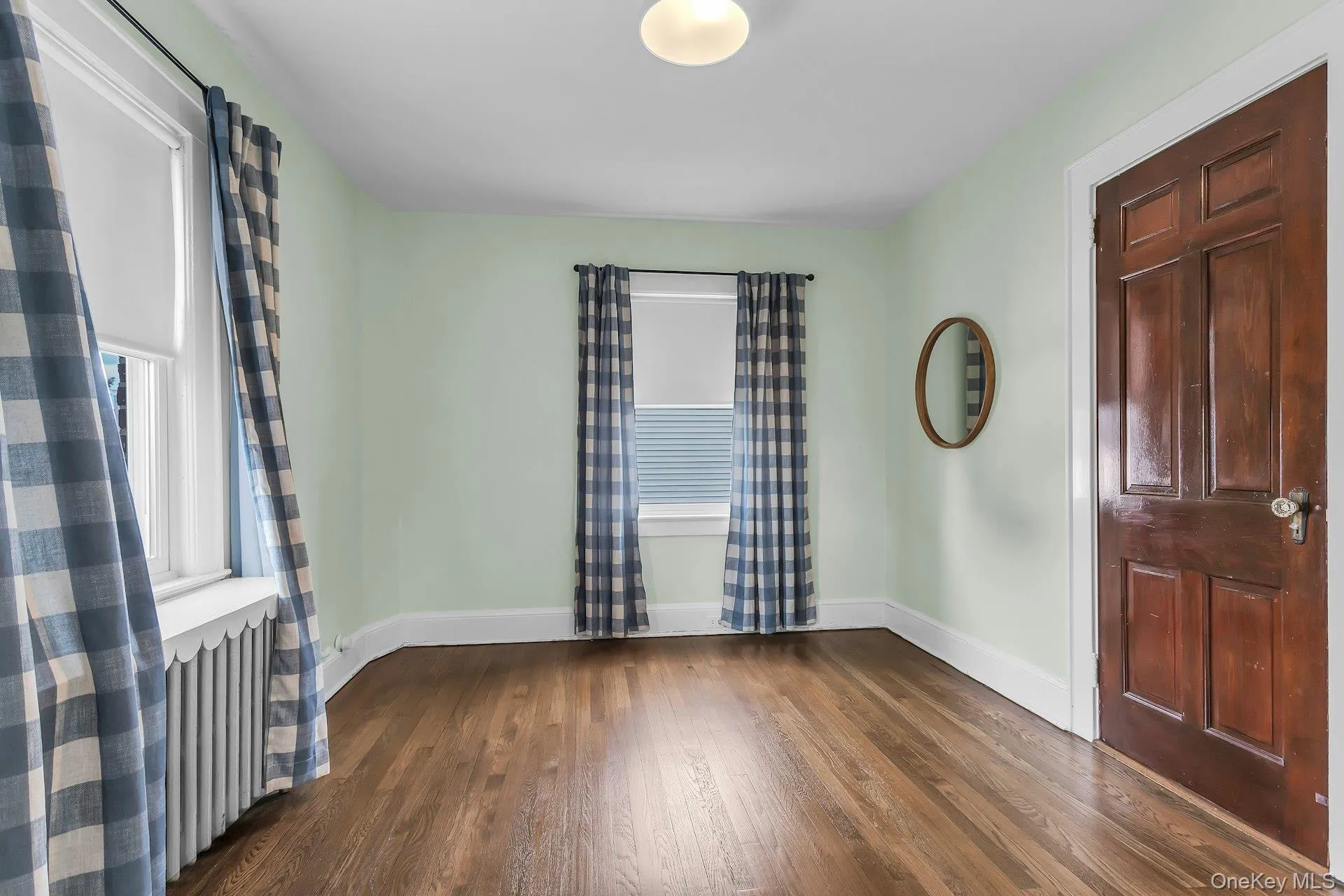 Hardwood flooring, painted walls, white trim, and a paneled wood door Hardwood flooring, painted walls, white trim, and a paneled wood door