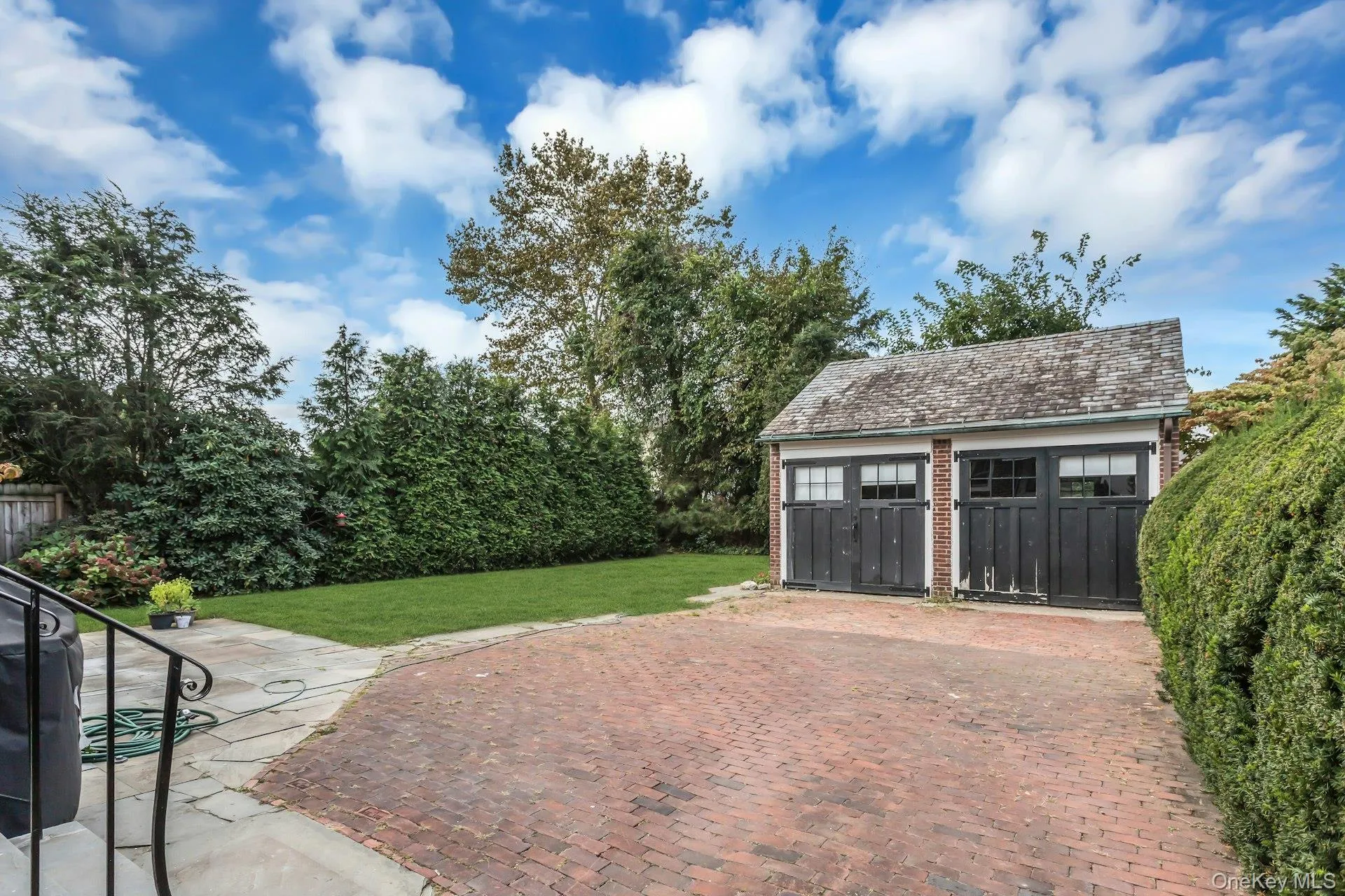 Two-car detached garage with overhead doors, brick-paved driveway, and a manicured lawn area Two-car detached garage with overhead doors, brick-paved driveway, and a manicured lawn area
