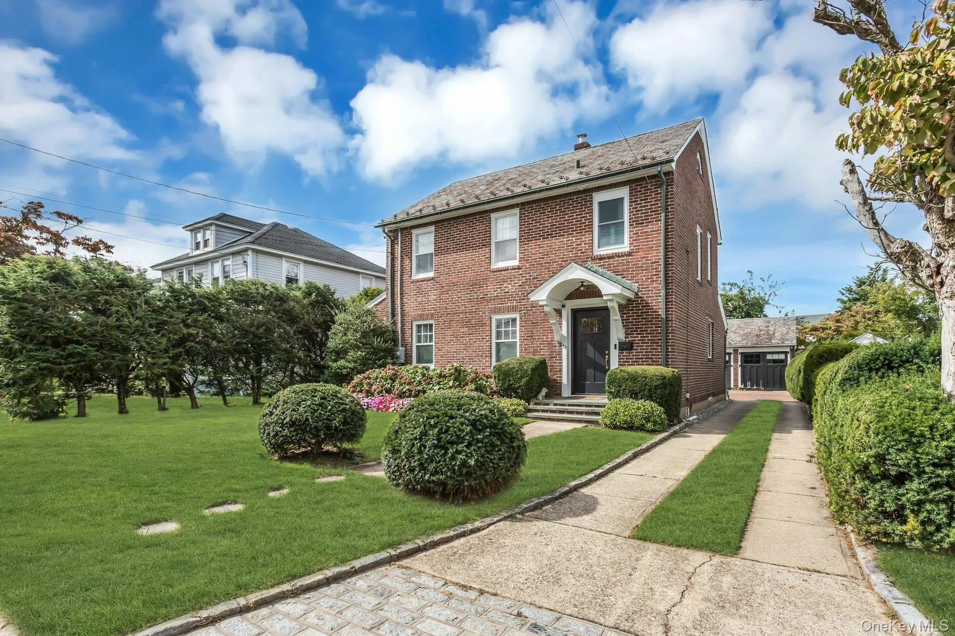 Brick exterior featuring a gabled roof and white window trim, long driveway and det garage Brick exterior featuring a gabled roof and white window trim, long driveway and det garage