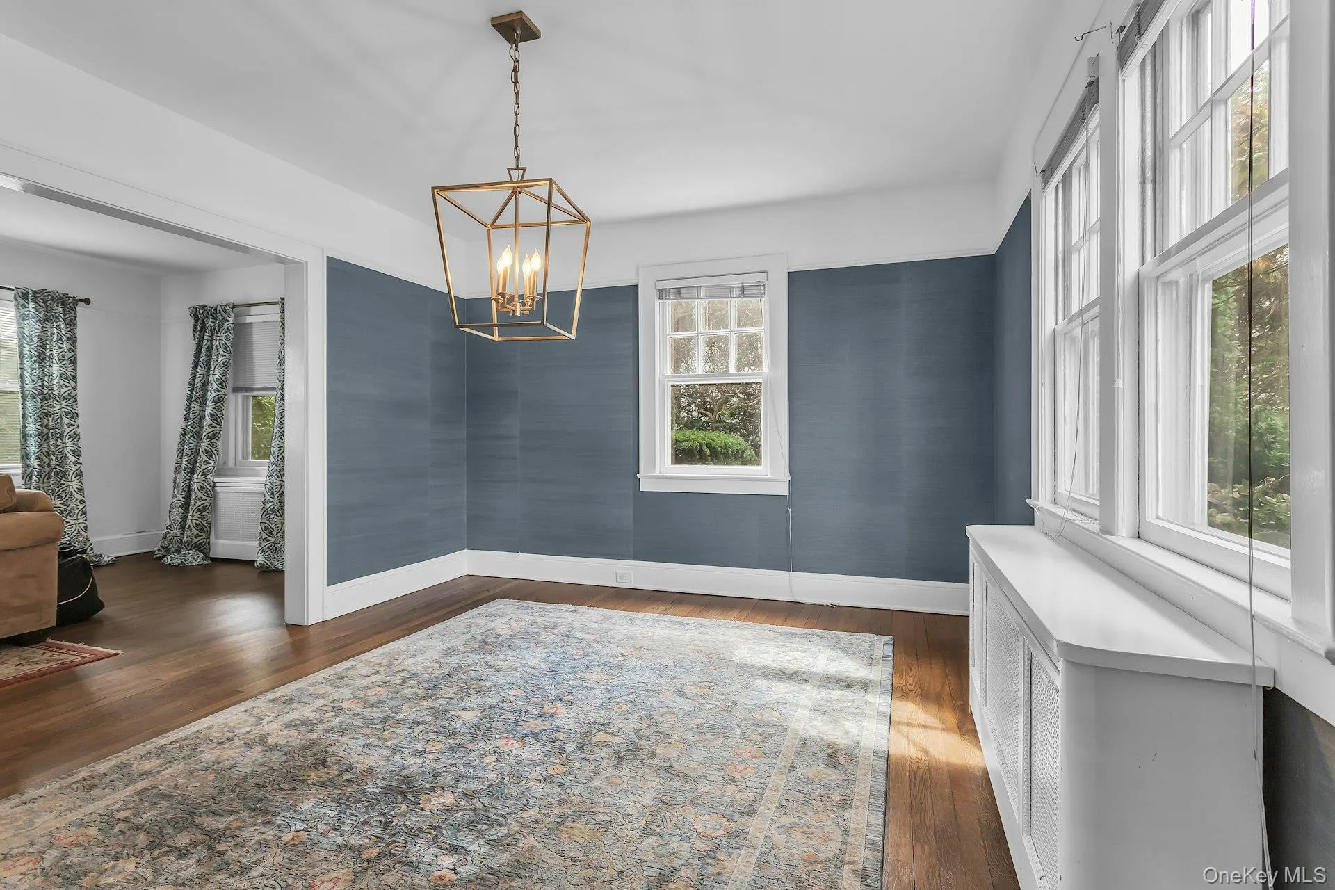 Hardwood flooring, painted accent walls, recessed archway, two pane windows, and a geometric chandelier Hardwood flooring, painted accent walls, recessed archway, two pane windows, and a geometric chandelier