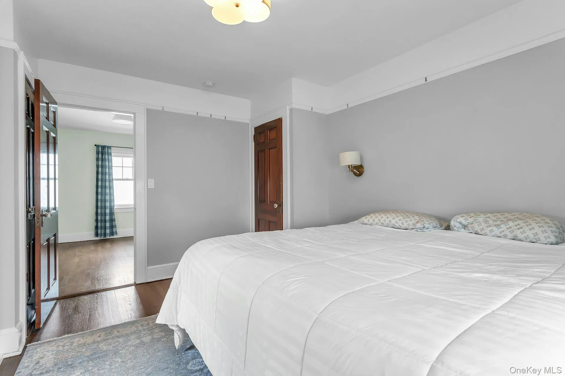 Recessed ceiling light fixture, wall-mounted sconce, wood-finish flooring, and a paneled wood door Recessed ceiling light fixture, wall-mounted sconce, wood-finish flooring, and a paneled wood door
