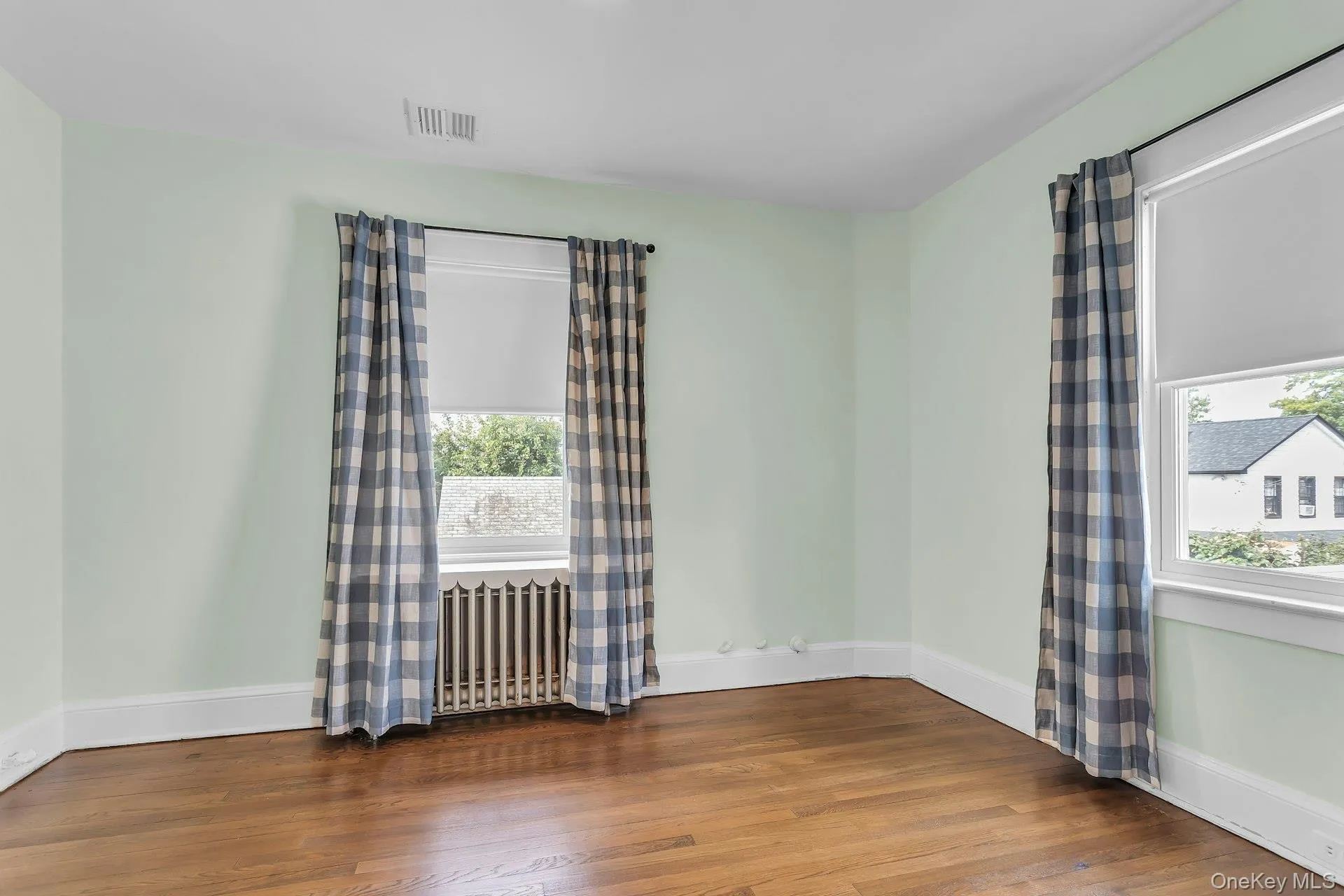 Hardwood flooring, two windows, radiator, and white trim Hardwood flooring, two windows, radiator, and white trim