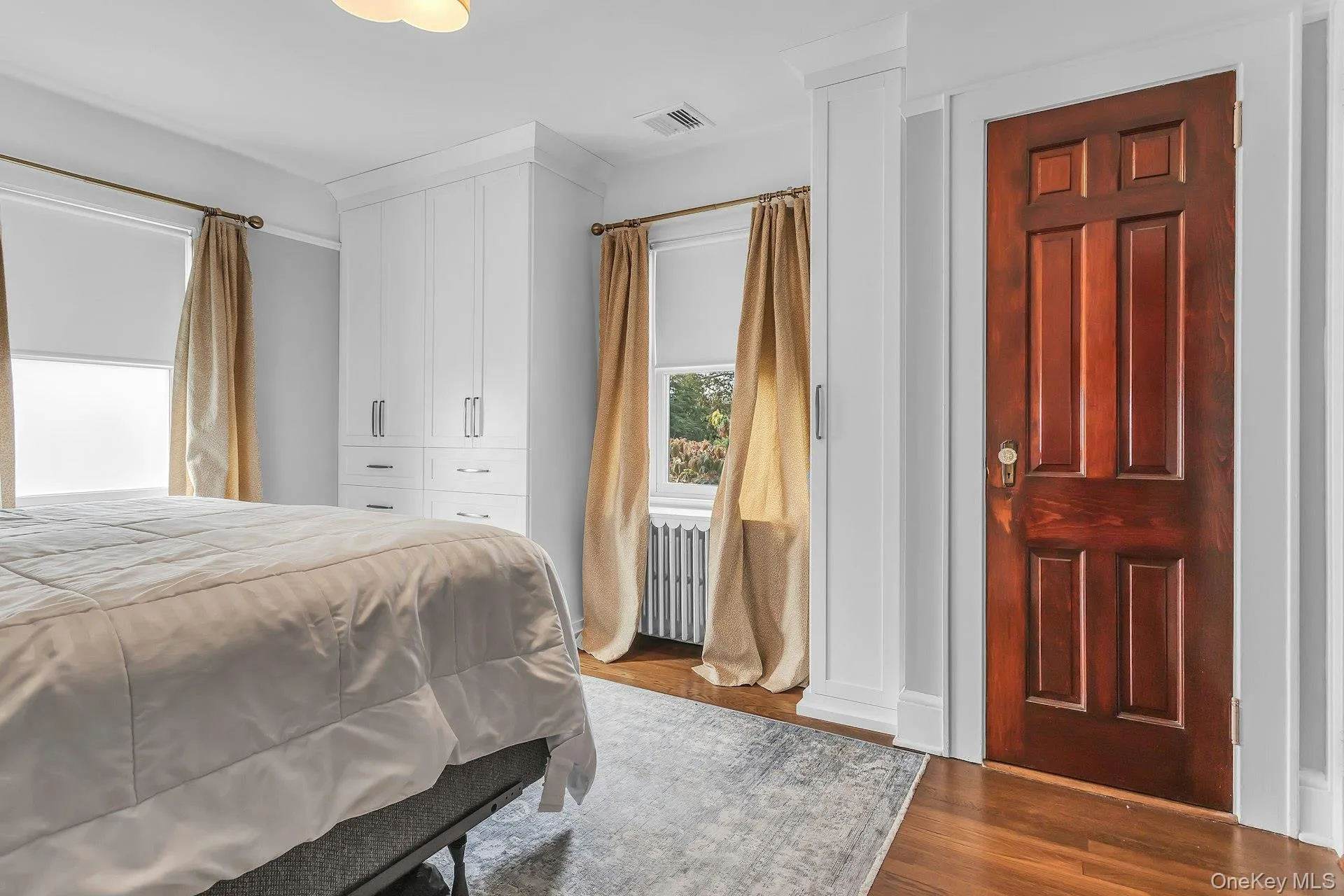 Hardwood flooring, built-in white cabinetry, custom window treatments, and a paneled wood door with decorative hardware Hardwood flooring, built-in white cabinetry, custom window treatments, and a paneled wood door with decorative hardware