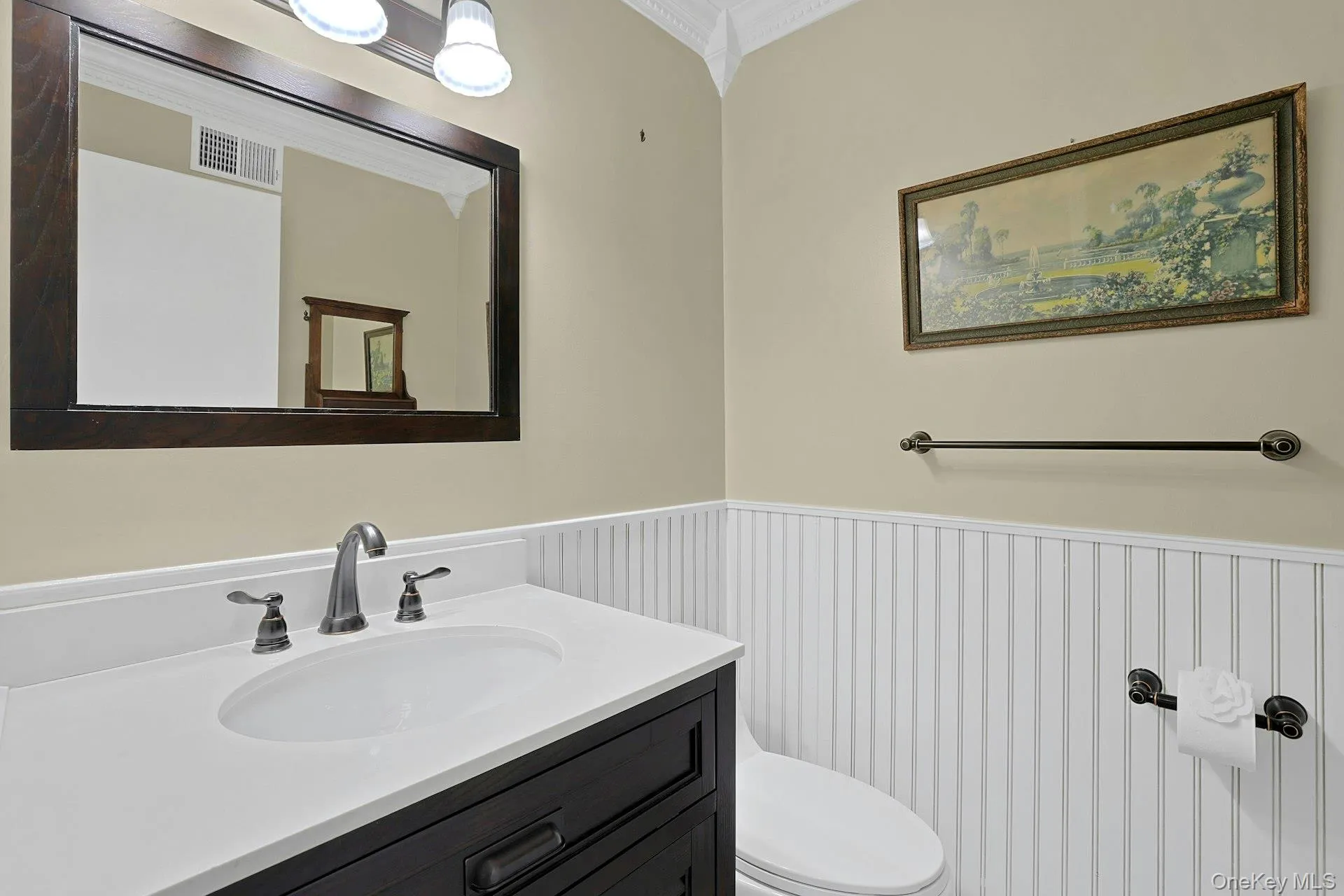 The updated hall half bathroom on the first floor features wainscotting, crown molding and a Corian vanity with a beautiful tri-fixture light. The updated hall half bathroom on the first floor features wainscotting, crown molding and a Corian vanity with a beautiful tri-fixture light.