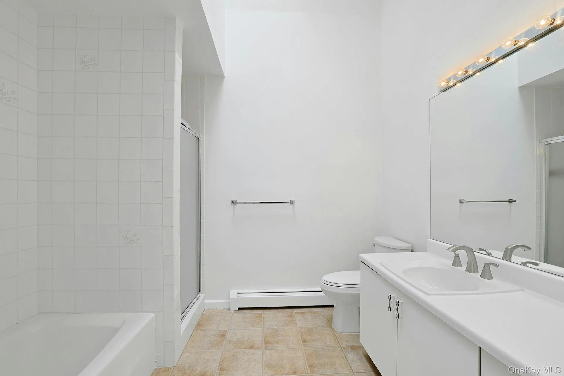 The primary bathroom, with tiled floor and a high ceiling that rises up to a skylight, is a private oasis. The long vanity is very usable, and there is a linen closet off-screen. The primary bathroom, with tiled floor and a high ceiling that rises up to a skylight, is a private oasis. The long vanity is very usable, and there is a linen closet off-screen.