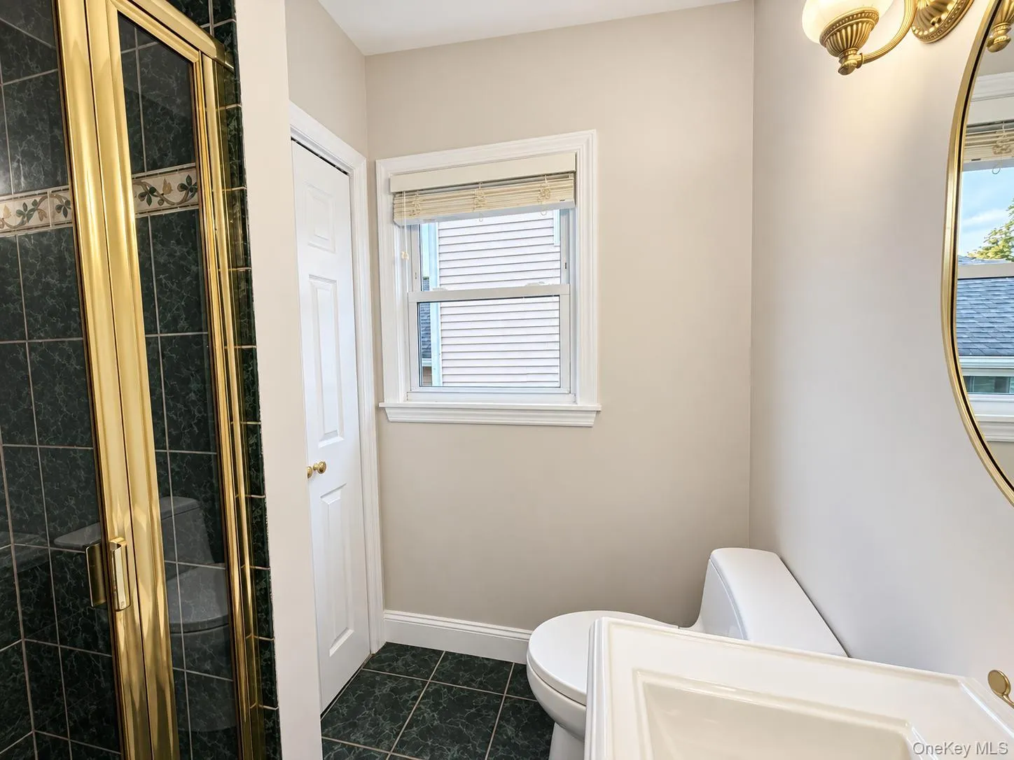 Shower enclosure with brass-finish framing and dark green tile Shower enclosure with brass-finish framing and dark green tile