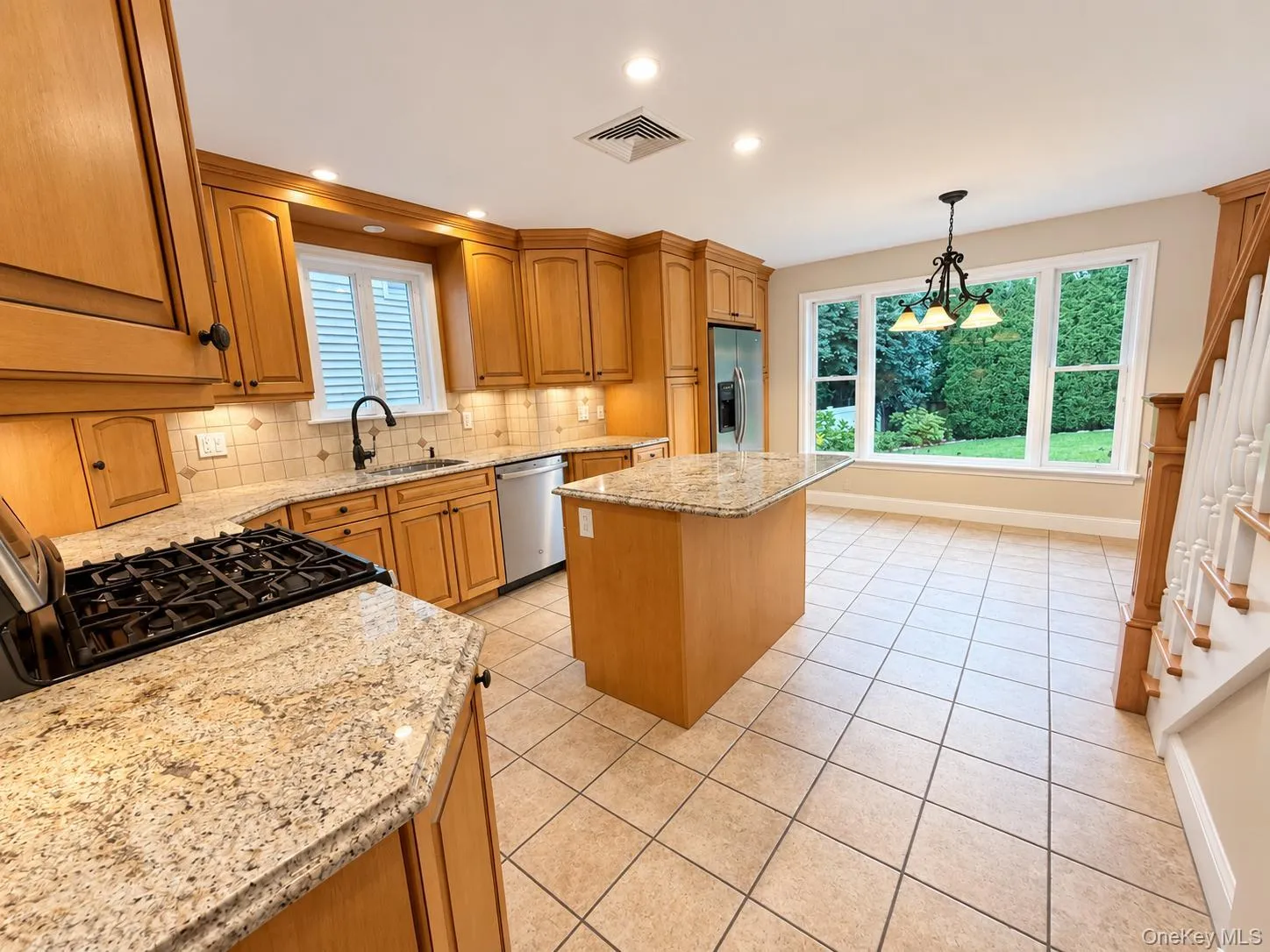 Kitchen featuring wood cabinetry, granite countertops, tile flooring, and stainless steel appliances Kitchen featuring wood cabinetry, granite countertops, tile flooring, and stainless steel appliances