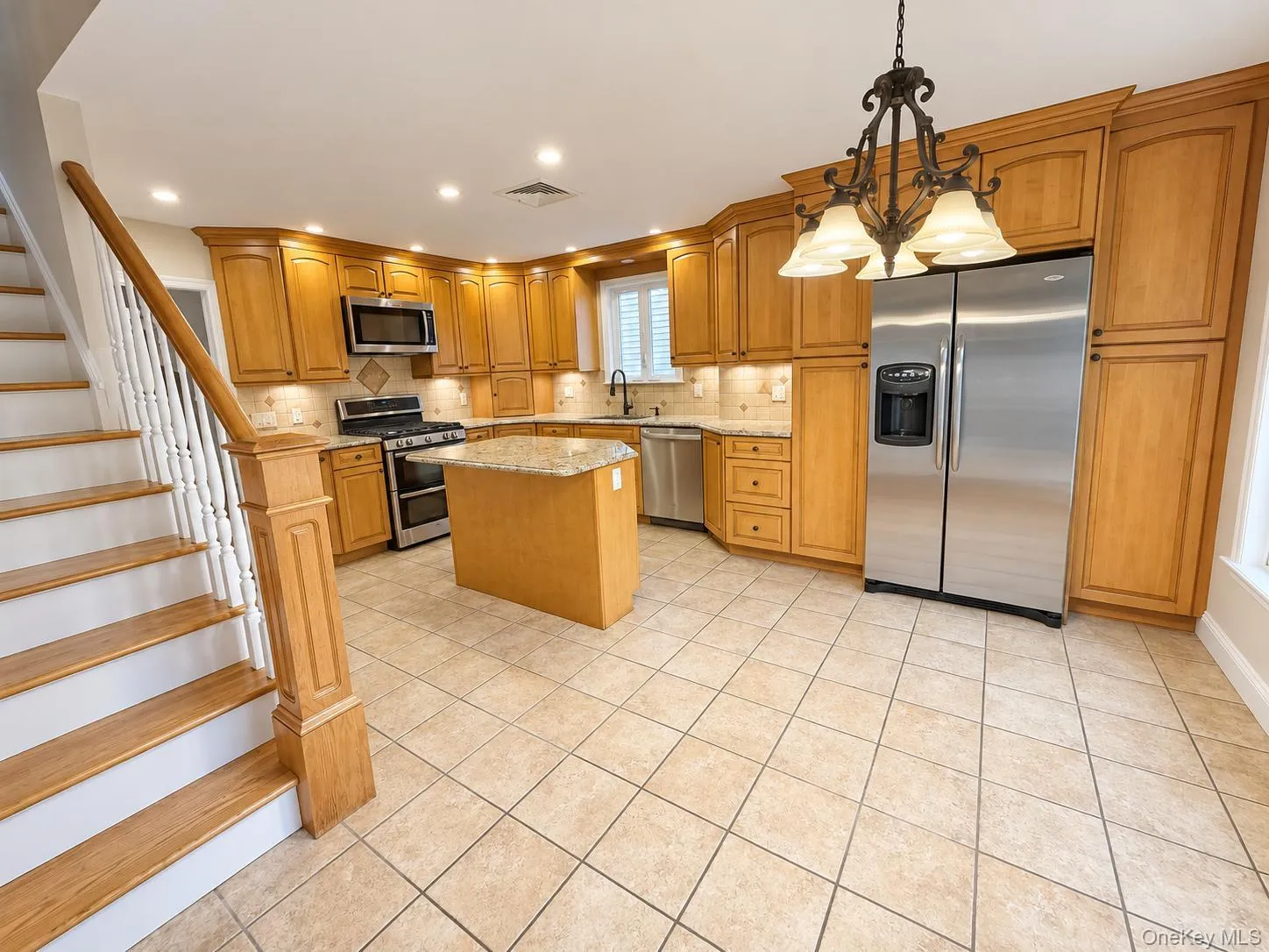 Kitchen featuring wood cabinetry, stainless steel appliances, a center island with a stone countertop, and tile flooring Kitchen featuring wood cabinetry, stainless steel appliances, a center island with a stone countertop, and tile flooring