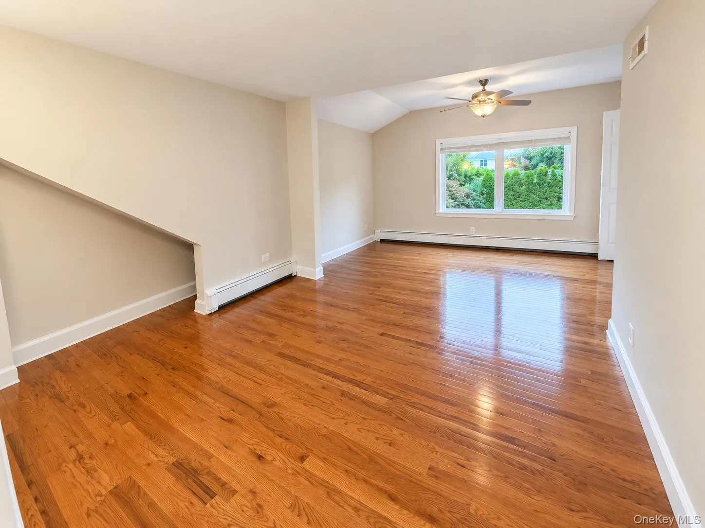 Vaulted ceiling with ceiling fan, wood-finish flooring, and a large window Vaulted ceiling with ceiling fan, wood-finish flooring, and a large window